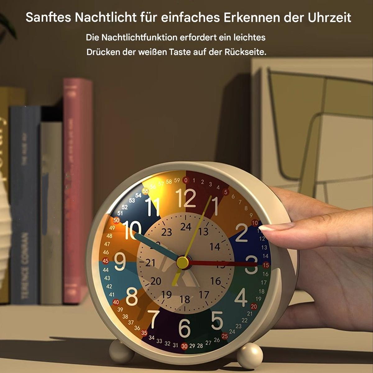 Ein cremefarbener Wecker mit buntem Zifferblatt, Zeiger auf 2:15. Eine Hand berührt die Uhr. Bücher im Hintergrund.
