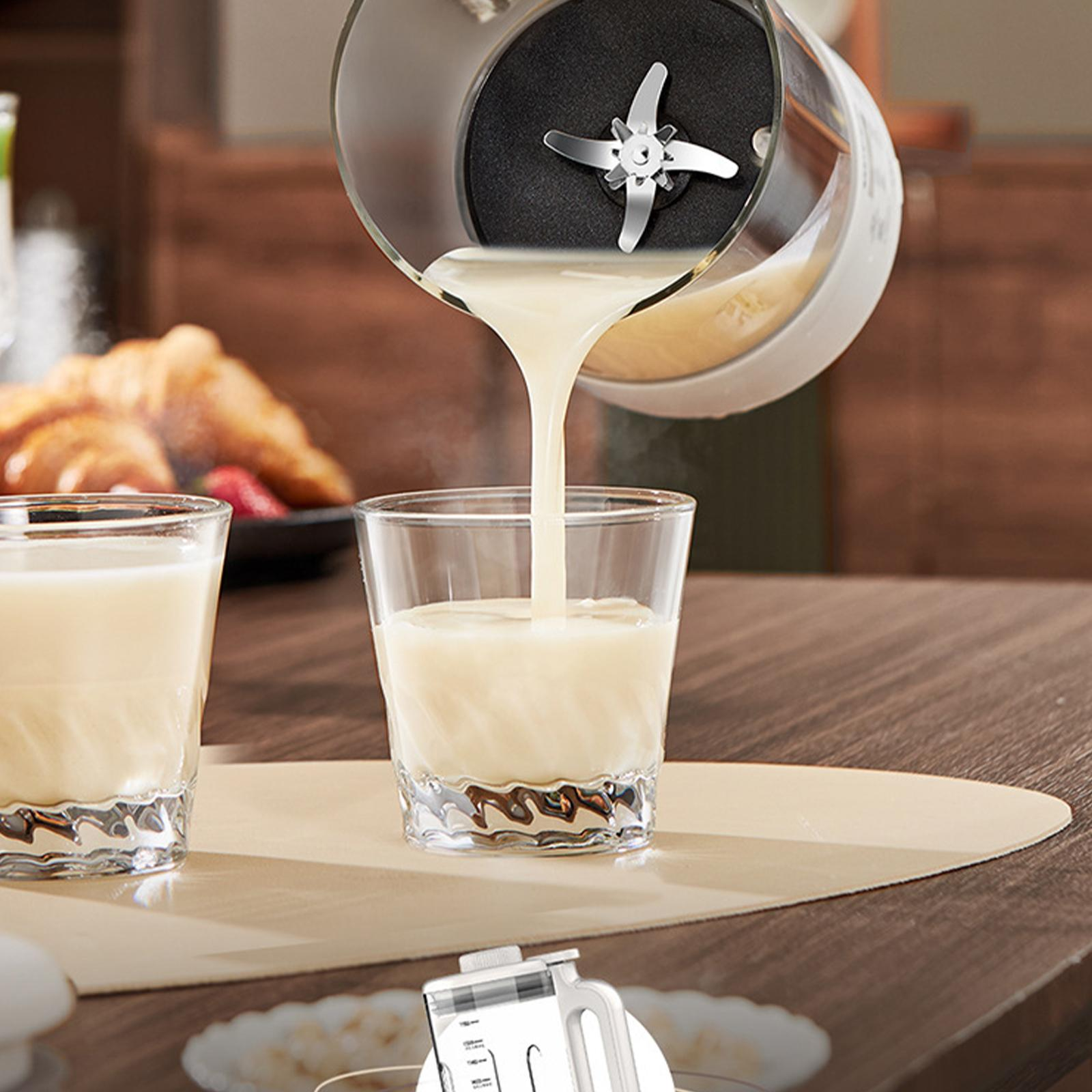 Ein Mixer gießt eine cremige Flüssigkeit in ein Glas. Ein weiteres Glas mit Flüssigkeit befindet sich links. Hintergrund hat Essen.