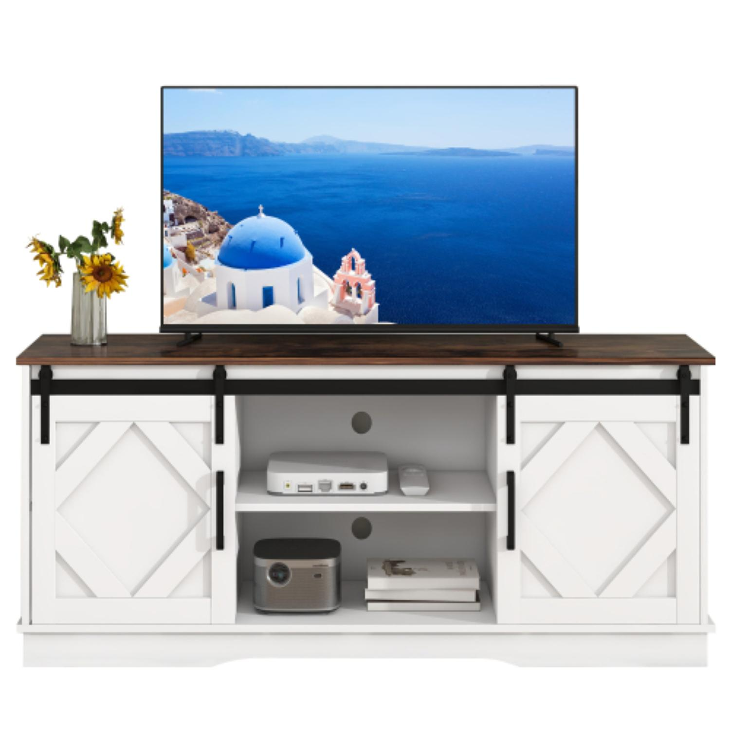 Ein weißer TV-Ständer mit brauner Oberseite, schwarzen Akzenten und Schiebetüren. Ein TV zeigt blaues Meer und weiße Gebäude. Sonnenblumen in einer Vase.
