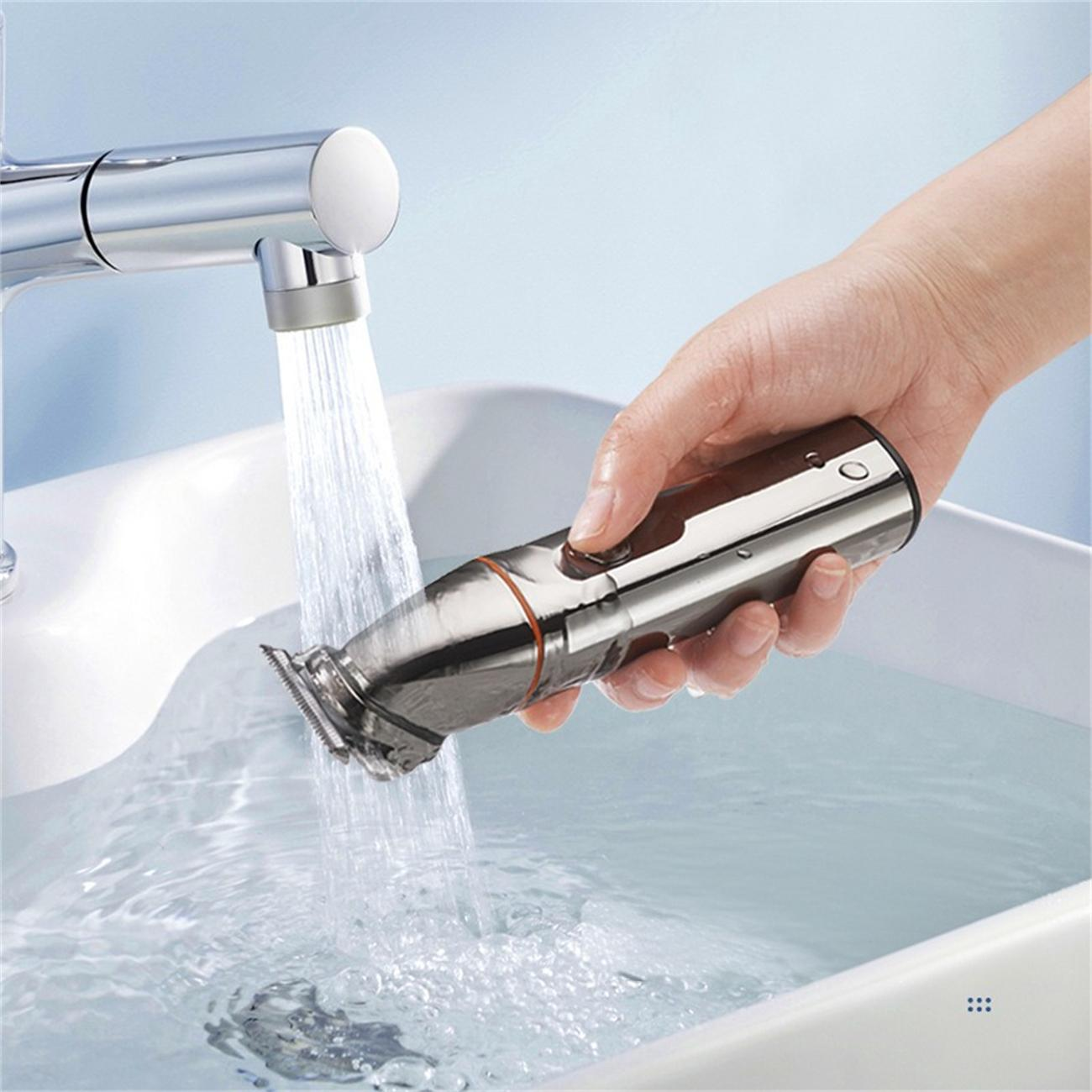 Eine Hand spült einen silbernen Elektrorasierer unter fließendem Wasser in einem weißen Waschbecken ab.