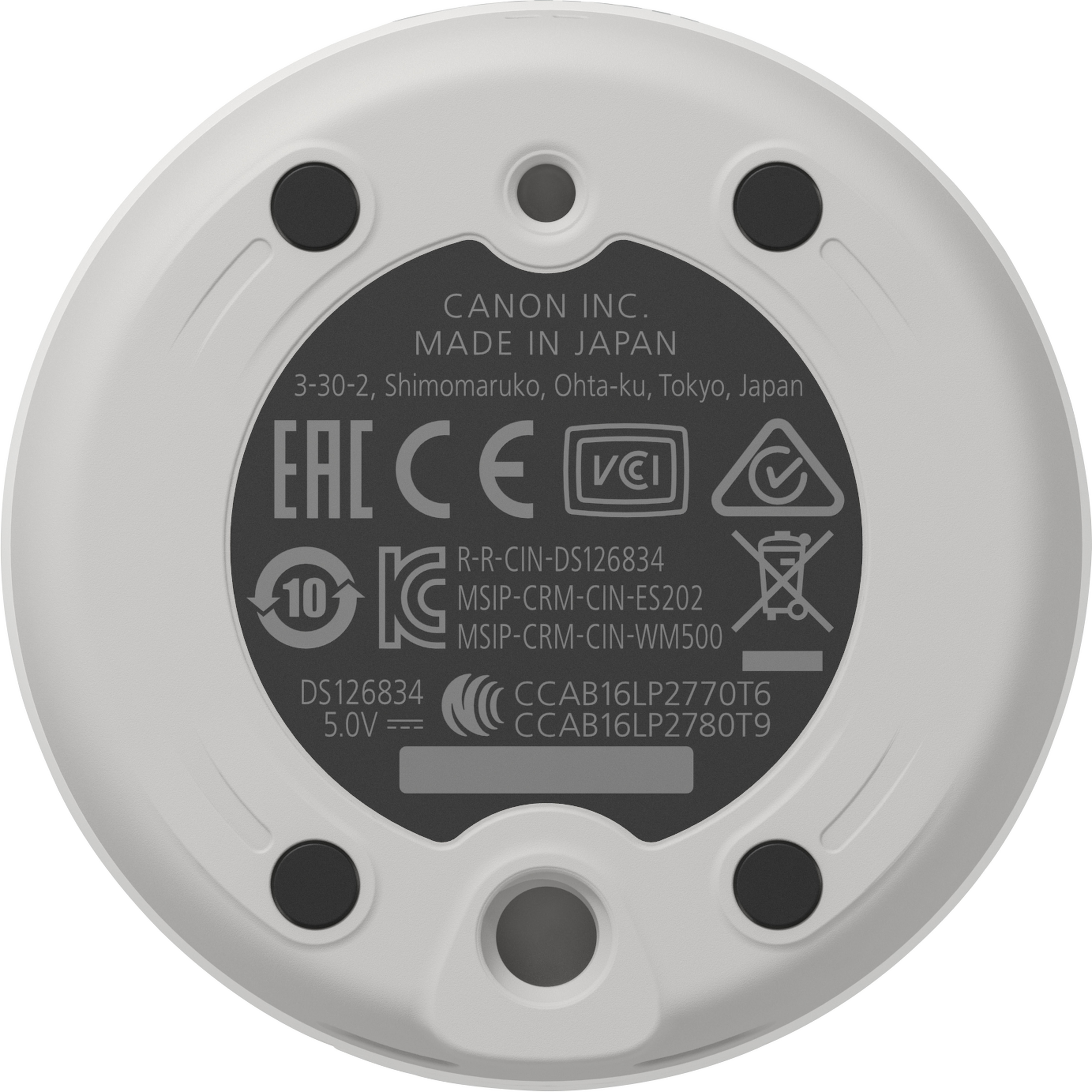 Base circular blanca con texto y símbolos negros. Etiqueta Canon Inc. Made in Japan visible.