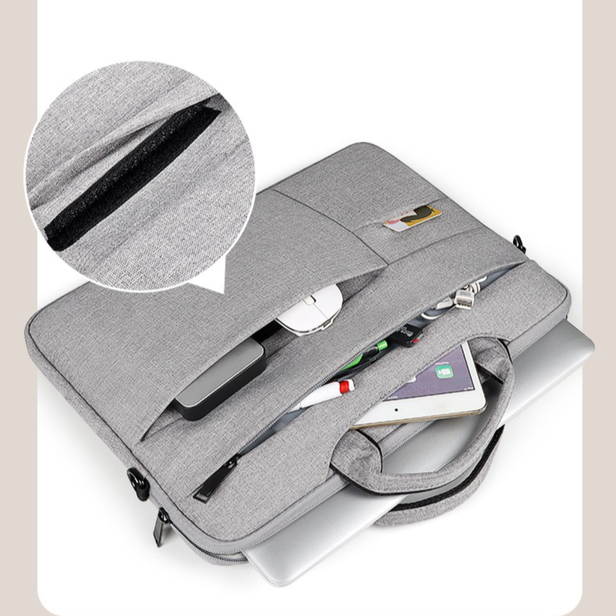 Graue Laptoptasche offen, Gegenstände innen. Enthält Maus, Tablet, Stift, Karte. Ein Laptop ist drin, Griff sichtbar.