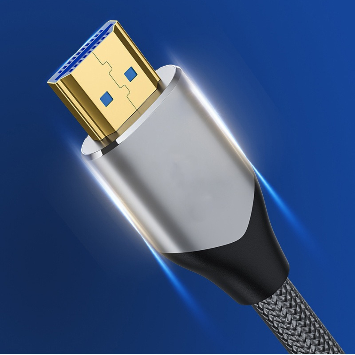 Nahaufnahme eines HDMI-Kabels. Goldfarbener Stecker mit blauen Quadraten und silbernem Gehäuse. Geflochtenes Kabel mit Schwarz und Grau. Blauer Hintergrund.