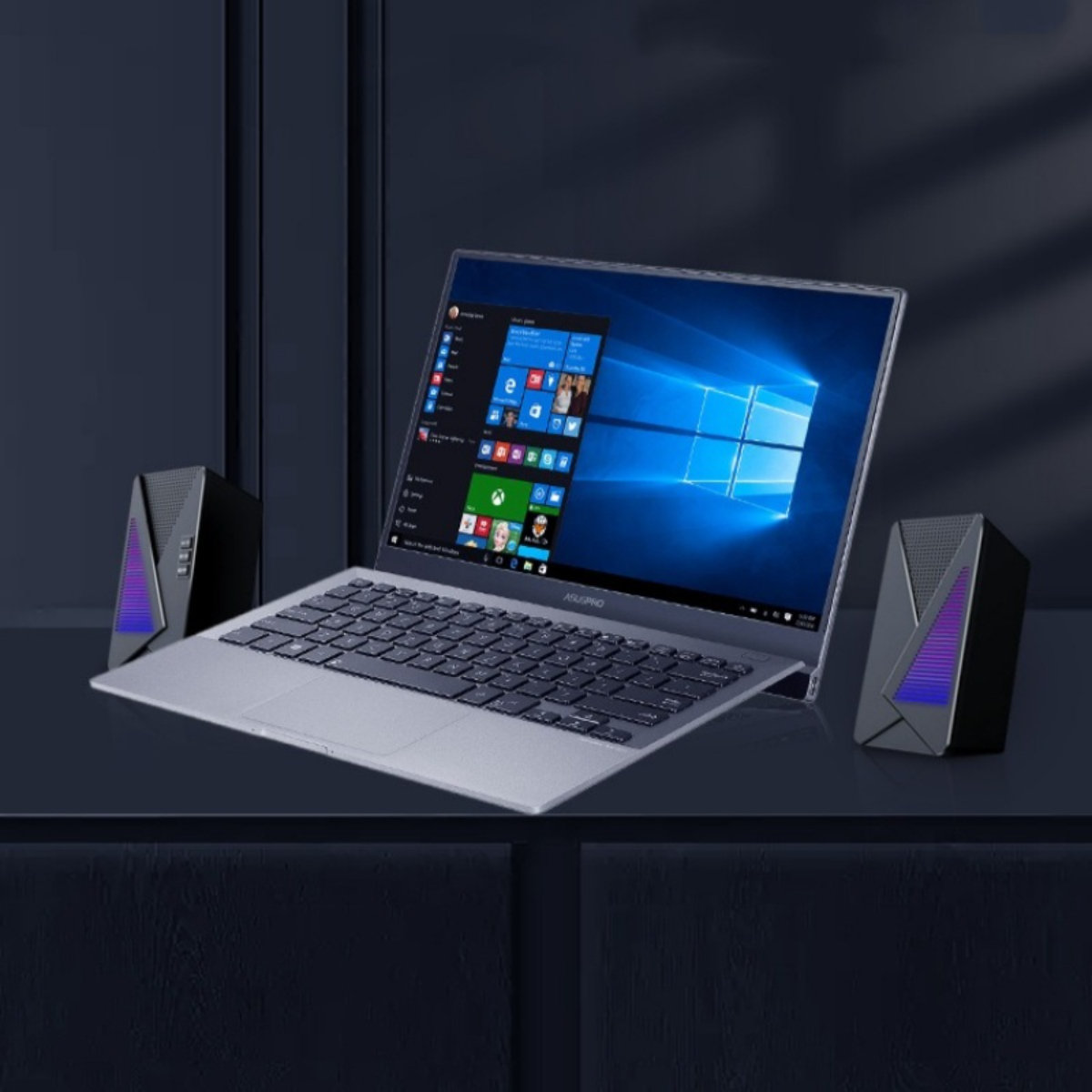 Ein Laptop mit Lautsprechern auf einer dunklen Oberfläche. Der Laptop-Bildschirm zeigt Windows. Der Hintergrund ist dunkelblau.