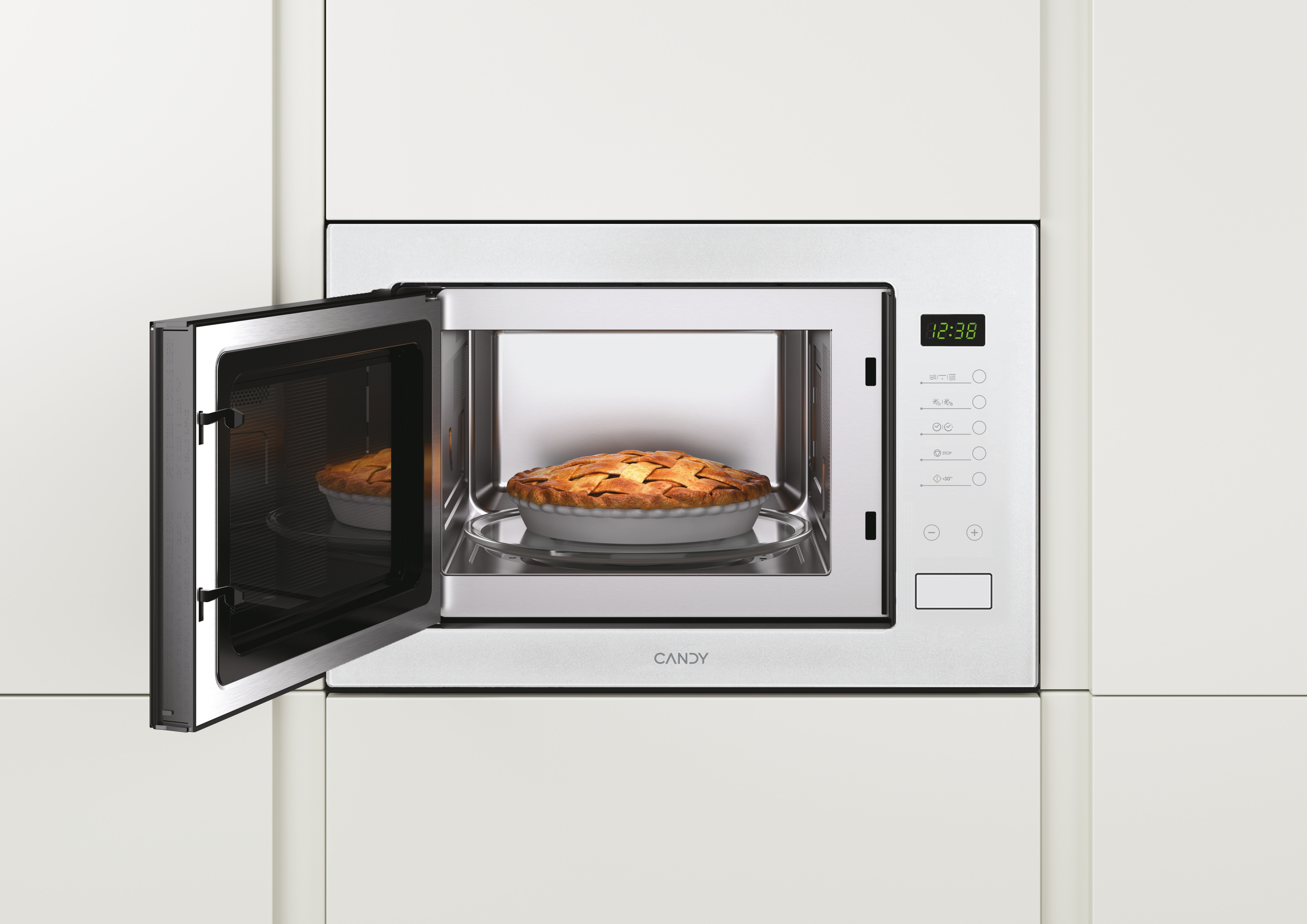 Mikrowelle mit offener Tür, zeigt einen Kuchen im Inneren. Die Uhrzeit ist 12:38. Die Mikrowelle ist in einem weißen Schrank eingebaut.
