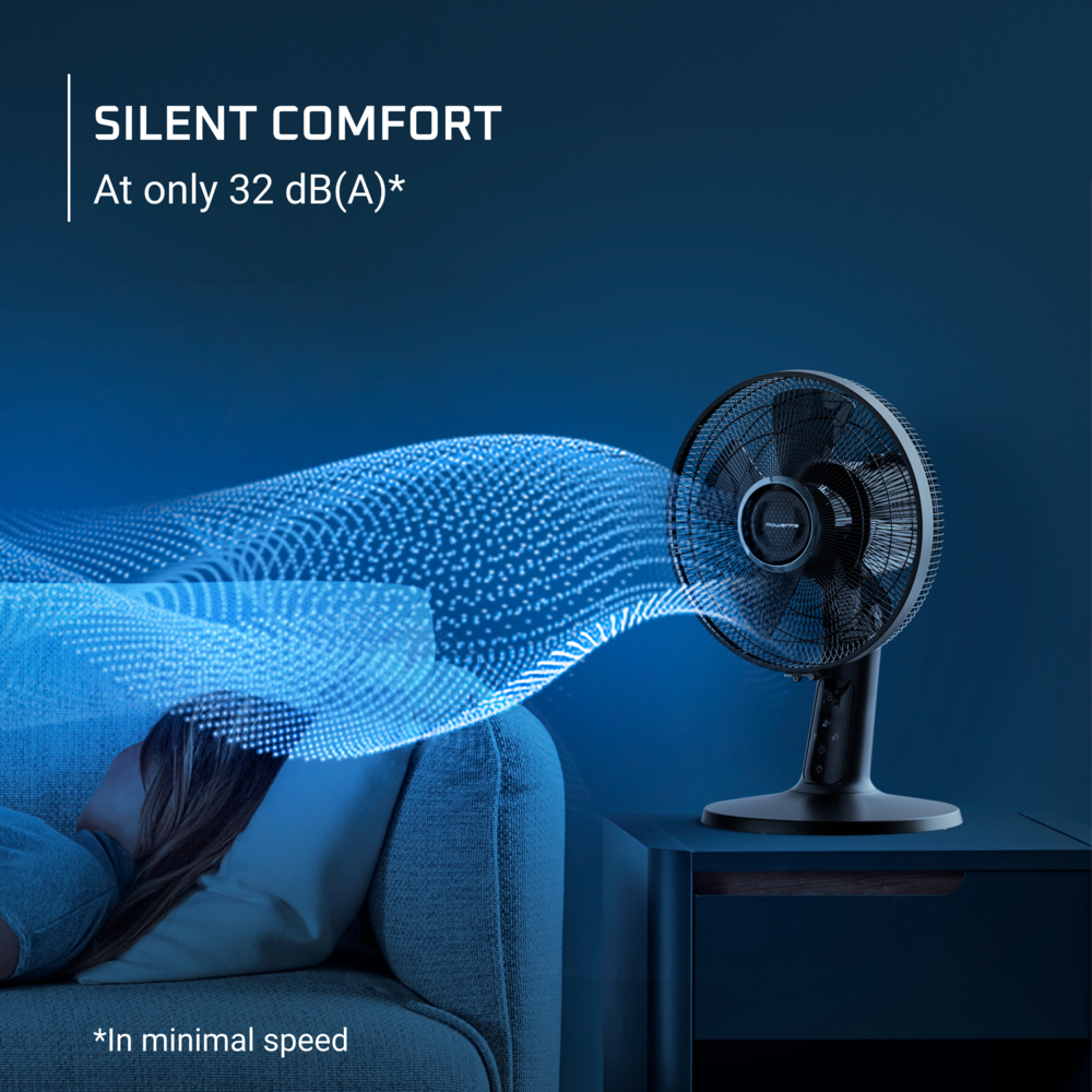 Ein schwarzer Ventilator steht auf einem blauen Tisch. Eine Person schläft auf einem Sofa. Text sagt 'Silent Comfort'. Der Ventilator bläst Luft.