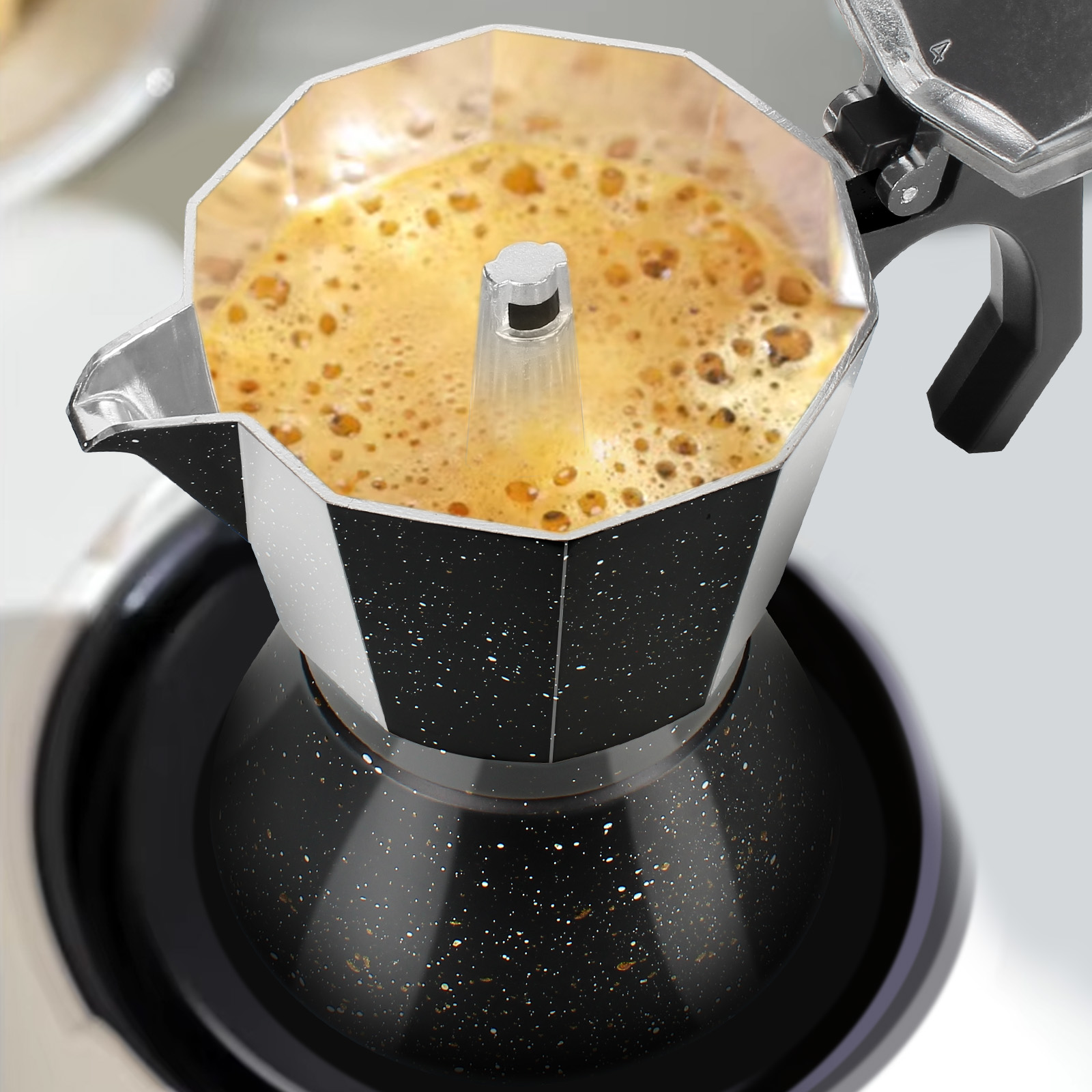 Nahaufnahme einer Mokkakanne beim Brühen von Kaffee. Die Kanne ist schwarz und silber, der Kaffee schaumig.