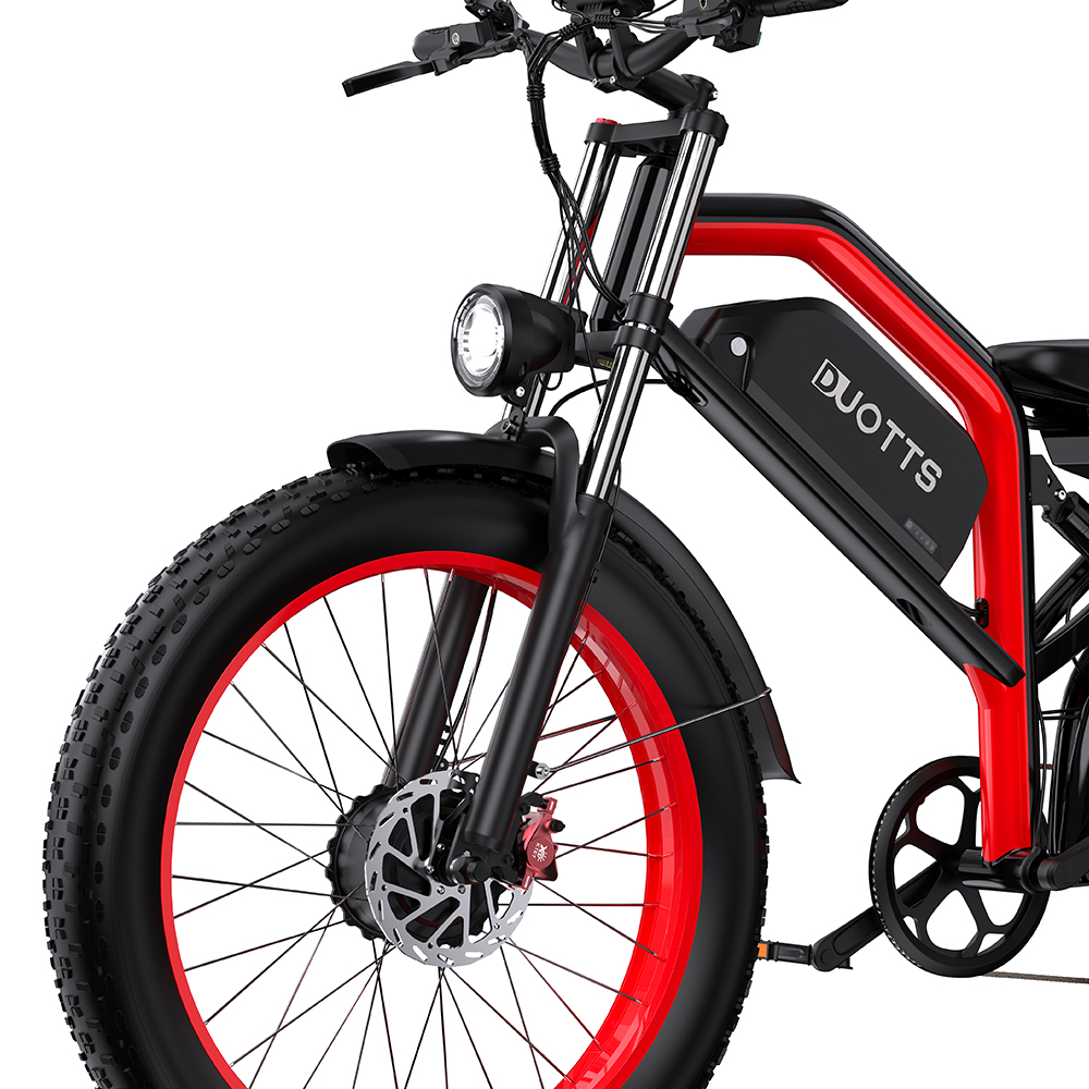 Primer plano de una bicicleta eléctrica roja y negra. La bicicleta tiene una gran rueda delantera, un faro y la marca DUOTTS.