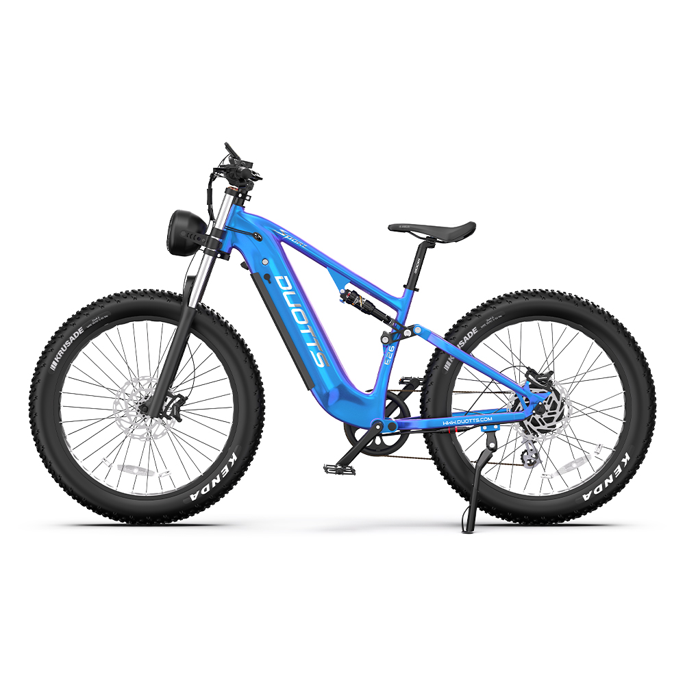 Bicicleta de montaña eléctrica azul sobre fondo blanco. Llantas negras con Kenda blanco. Faro delantero y logo DUOTTS visibles.