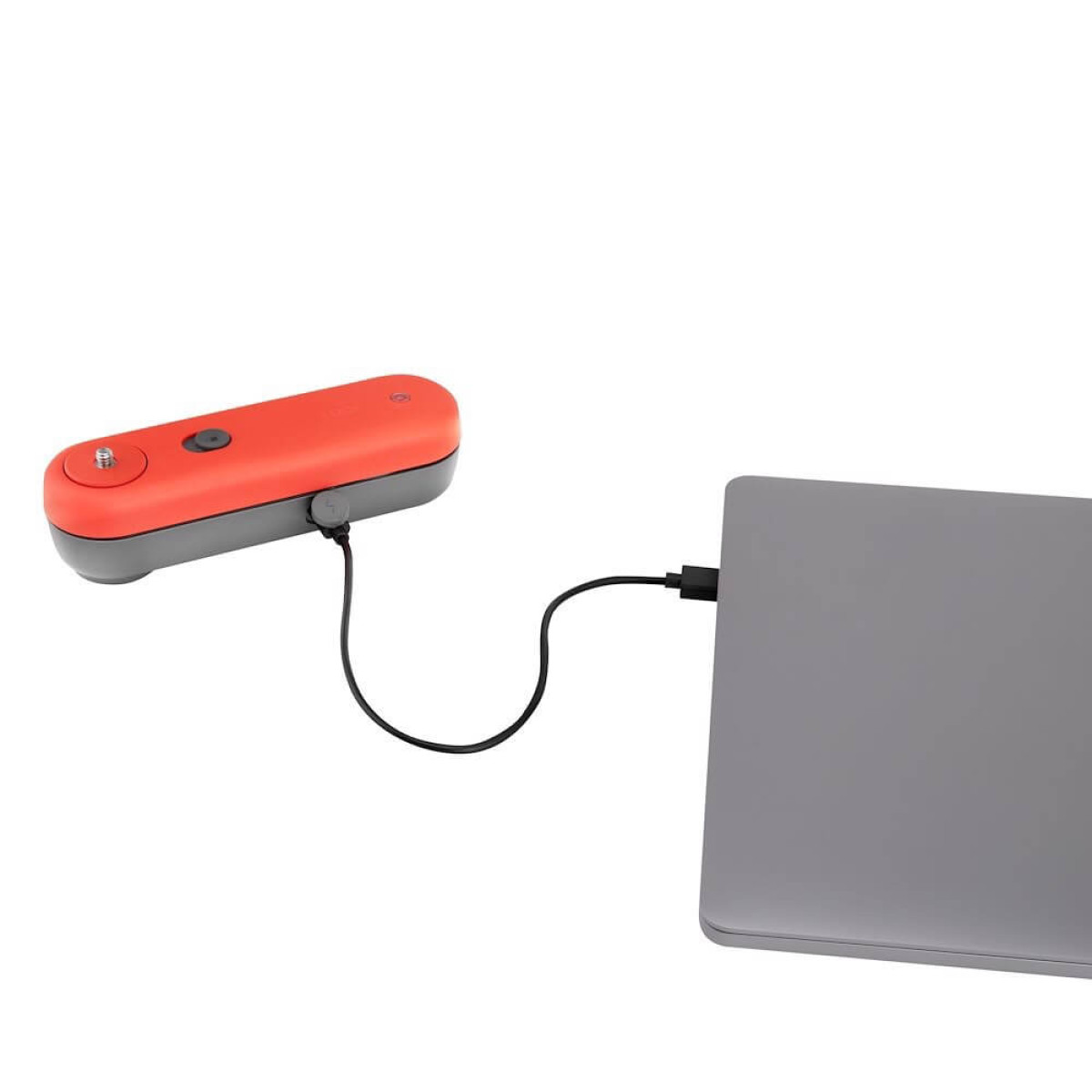 Czerwone i szare urządzenie ładujące laptopa za pomocą czarnego kabla. Laptop jest szary. Białe tło.