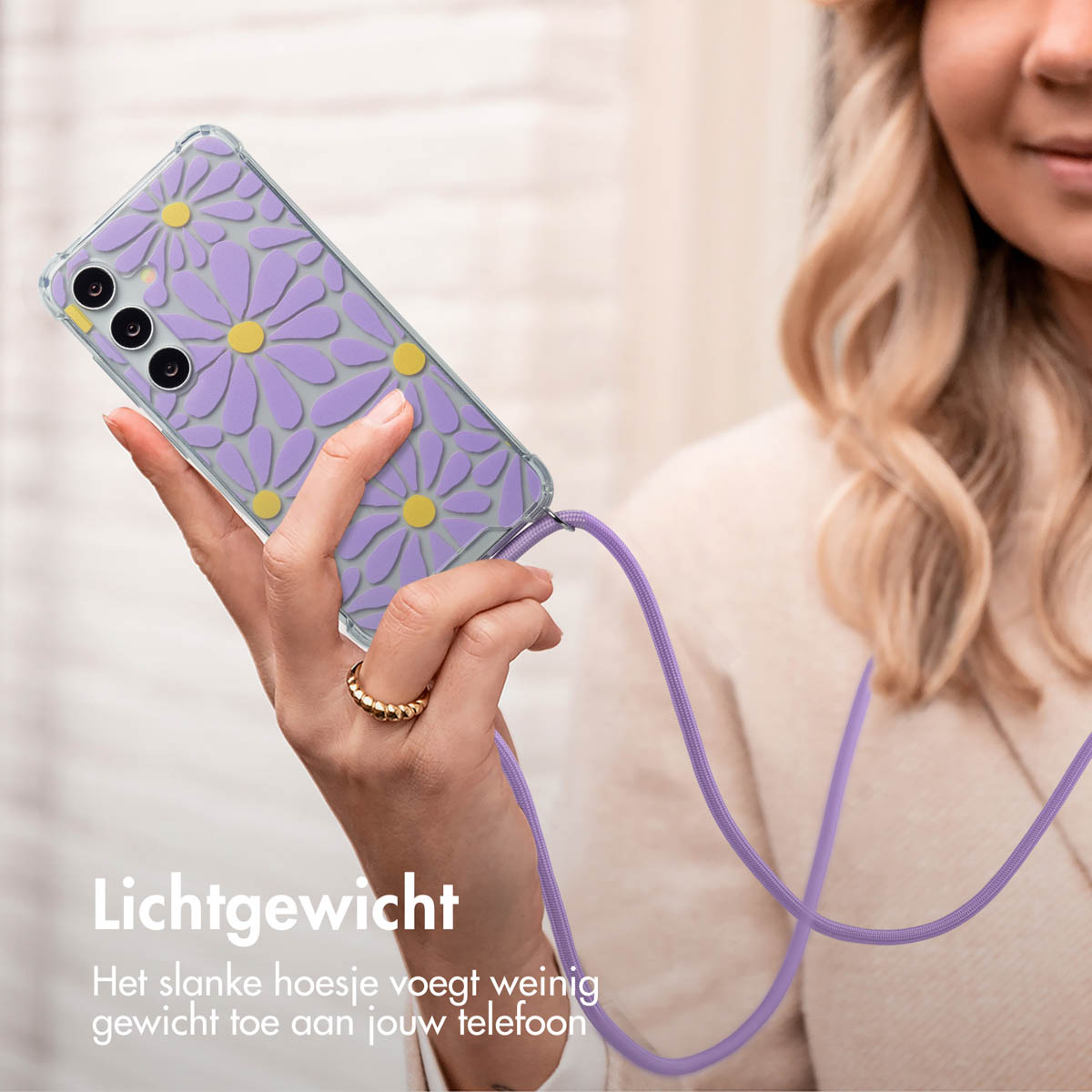 Femme tenant un téléphone avec une coque de marguerite violette. Bague en or et cordon violet.
