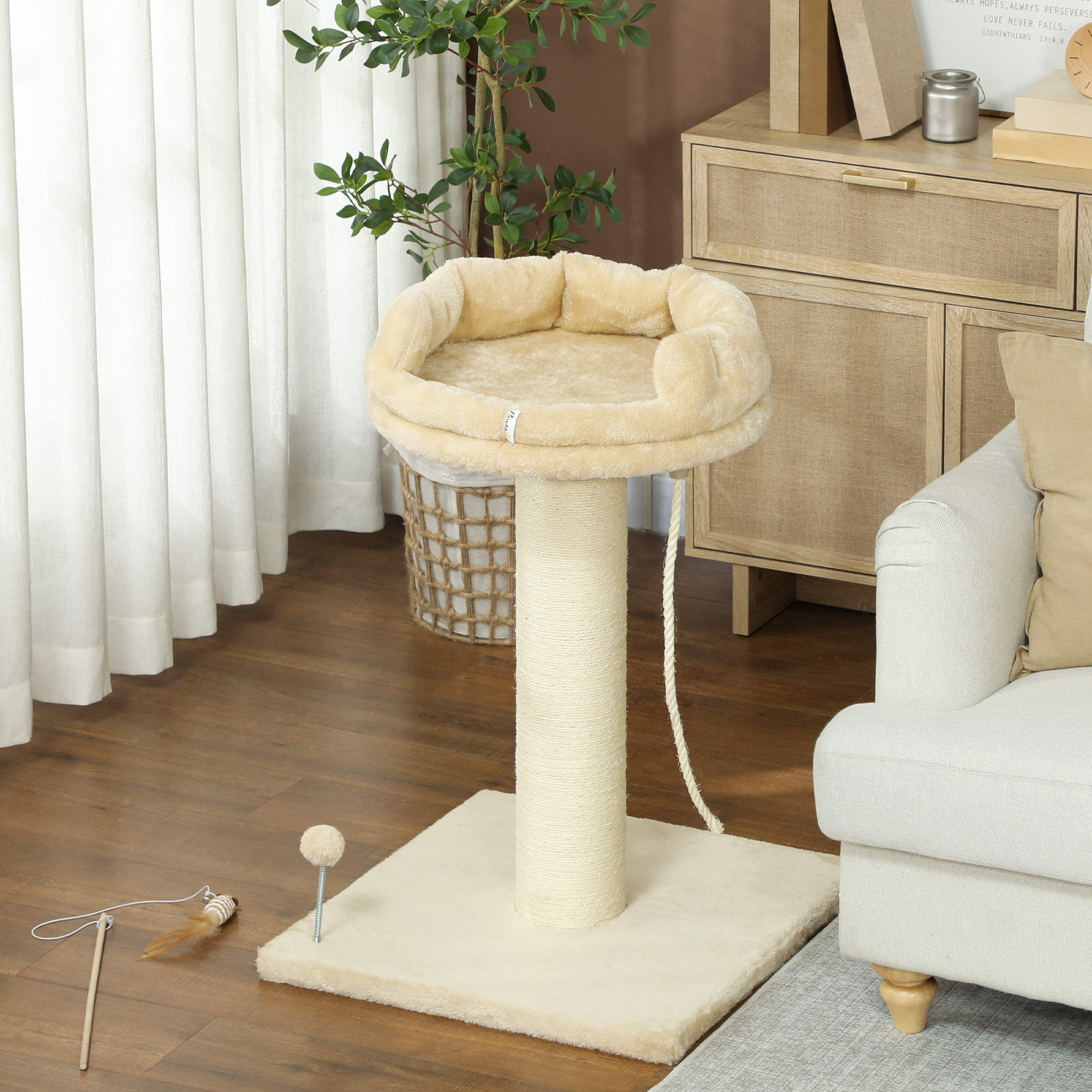 Un rascador para gatos con base beige, poste rascador, cama y juguete, colocado en un suelo de madera.