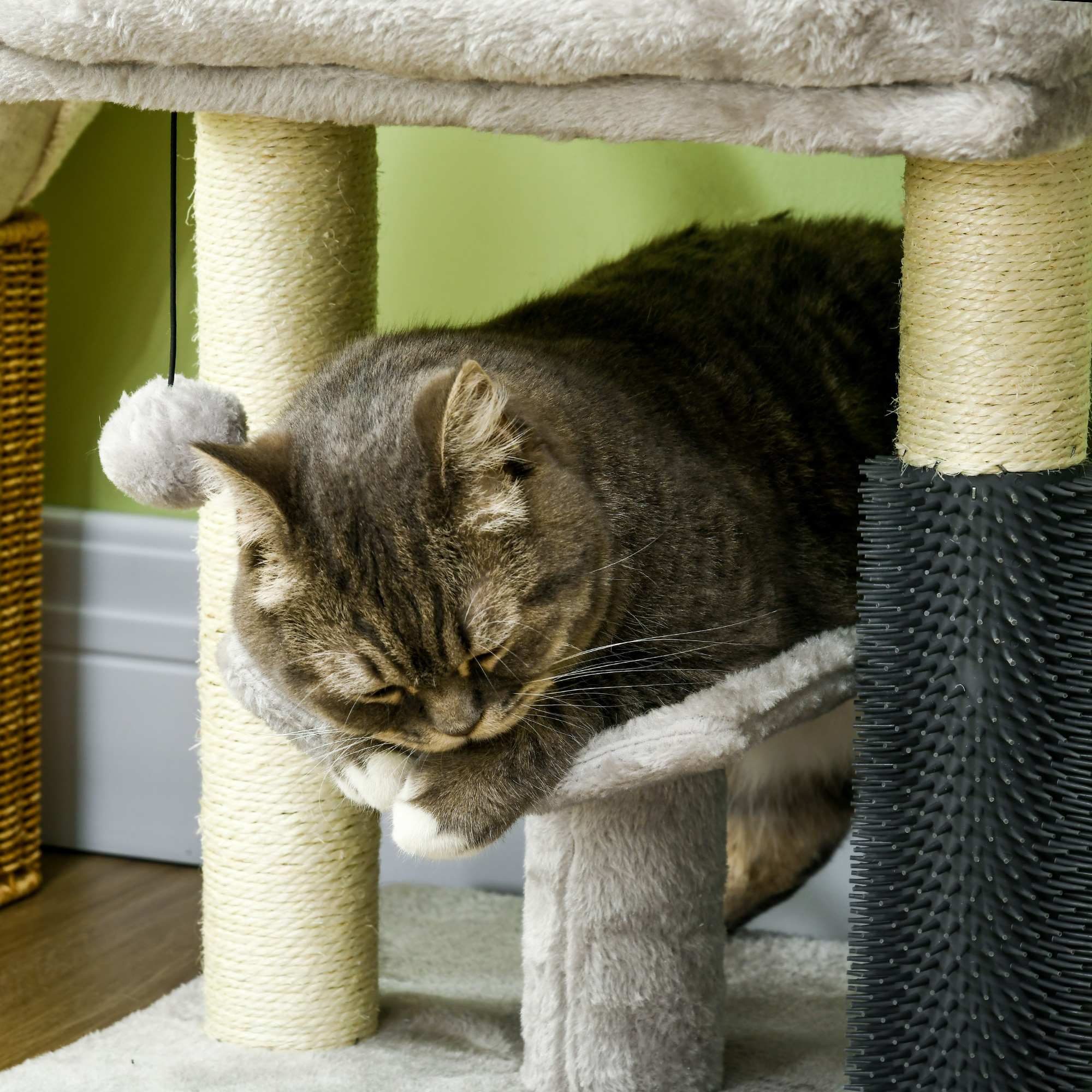 Gatto che riposa su una piattaforma per alberi per gatti, con un tiragraffi nelle vicinanze.