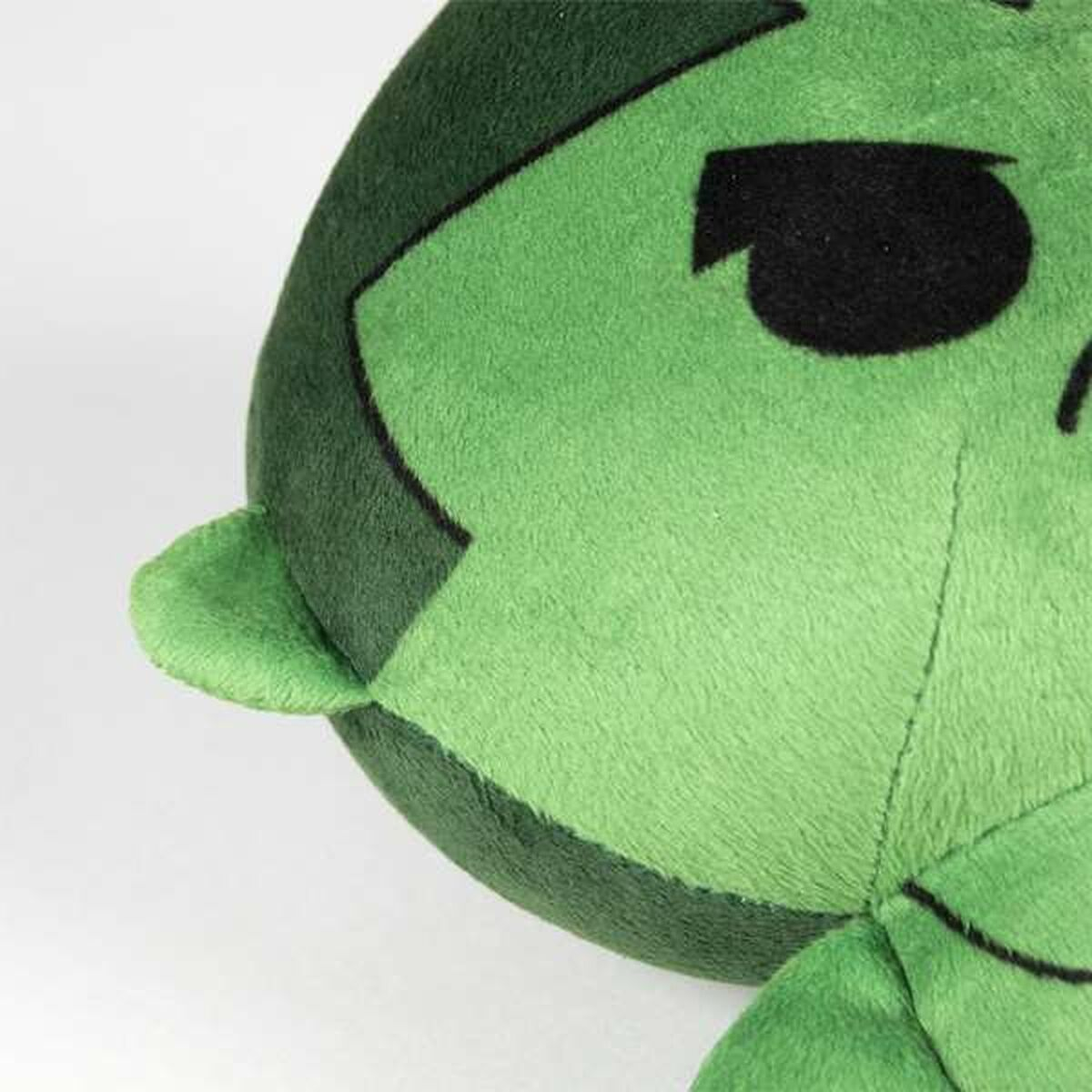 Un primo piano del viso di un peluche verde di Hulk. Lo sfondo è bianco.