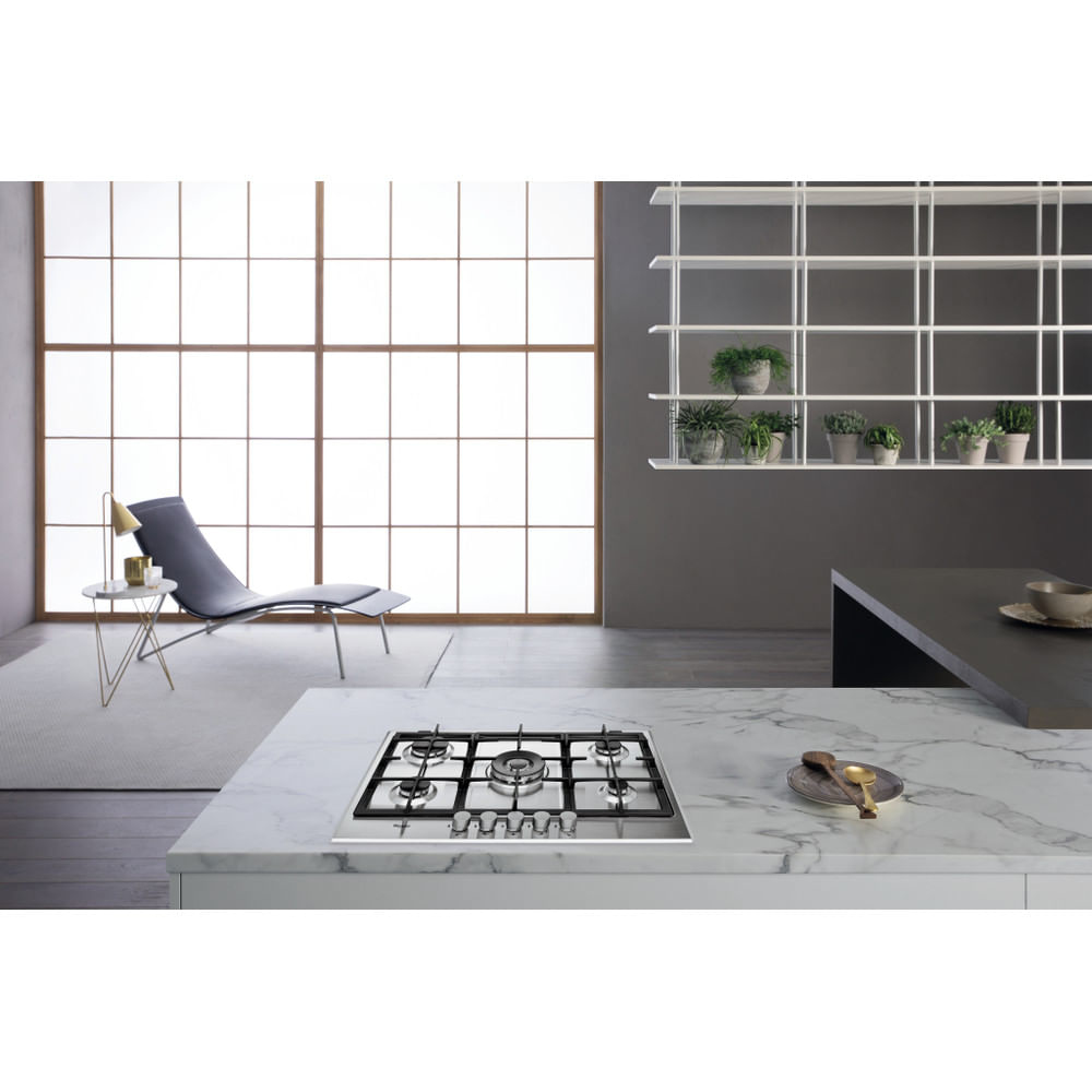Interni cucina con piano cottura a gas su ripiano in marmo. Sedia, tavolino e scaffali visibili.