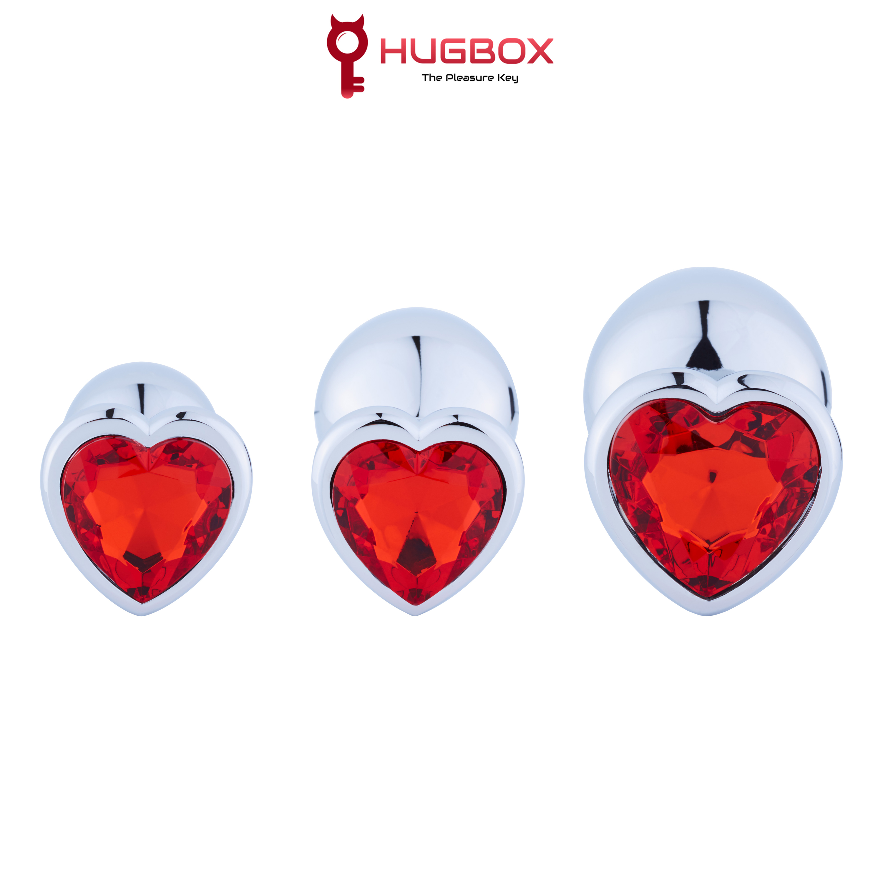 Tres tapones anales plateados con gemas rojas en forma de corazón, de varios tamaños, sobre fondo blanco.