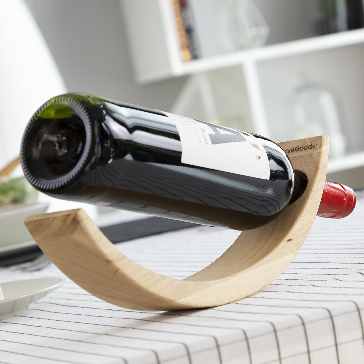 Portabottiglie in legno con bottiglia di vino nero su un tavolo.