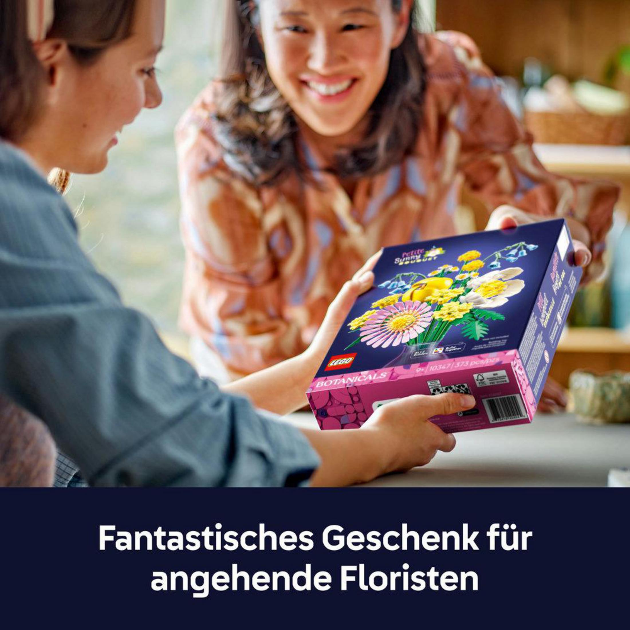 Dwie osoby trzymające pudełko Lego z kwiatami.