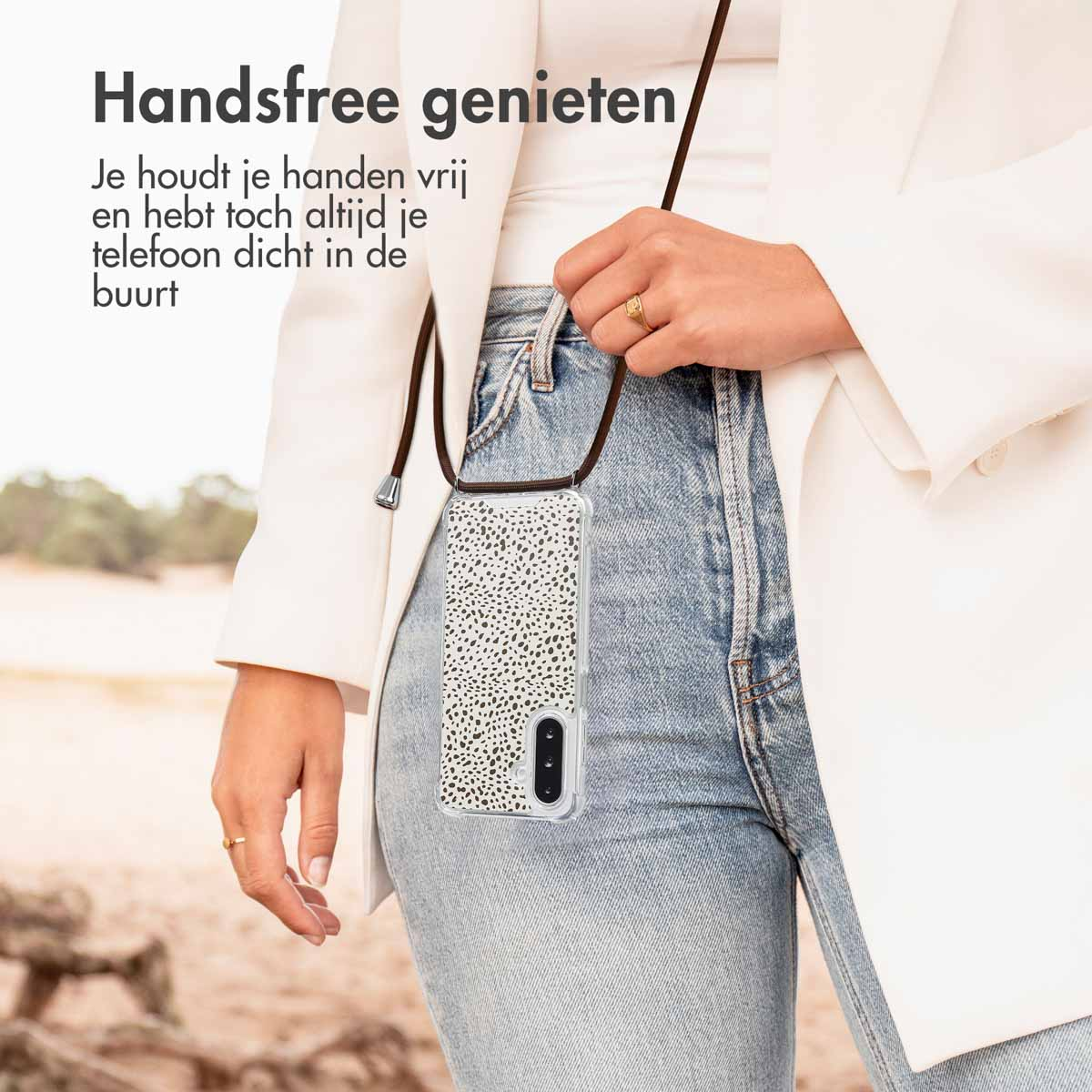 Een persoon die een witte blazer en jeans draagt, met een telefoonhoesje met een stippenpatroon.