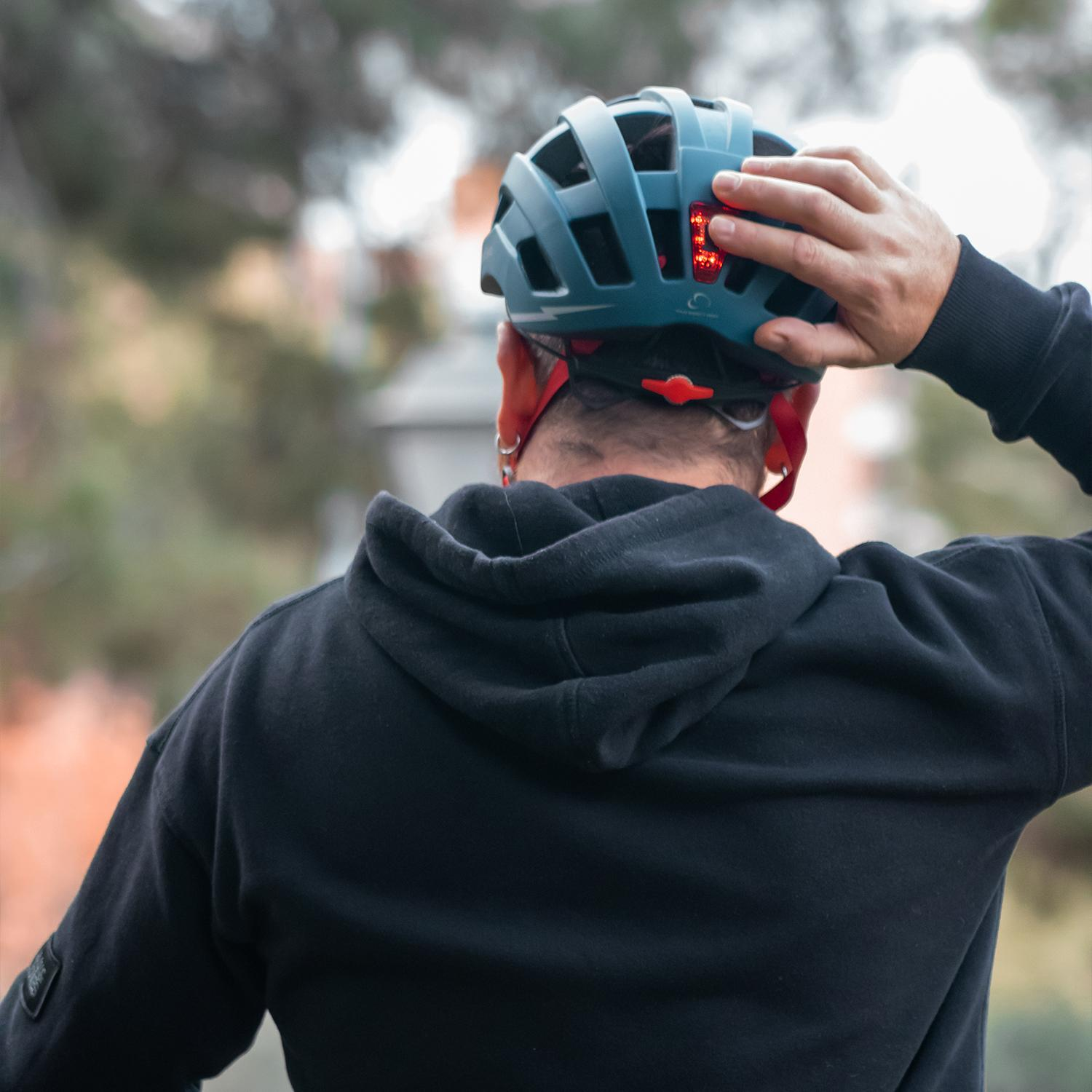 Un hombre con sudadera negra ajusta su casco. Enfoque en la parte trasera.
