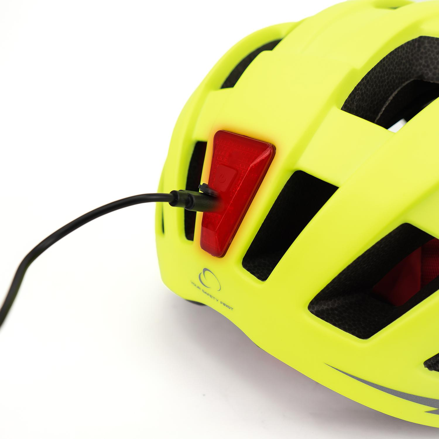 Primer plano de un casco de bicicleta amarillo con puerto de carga en luz roja. Cable negro conectado.