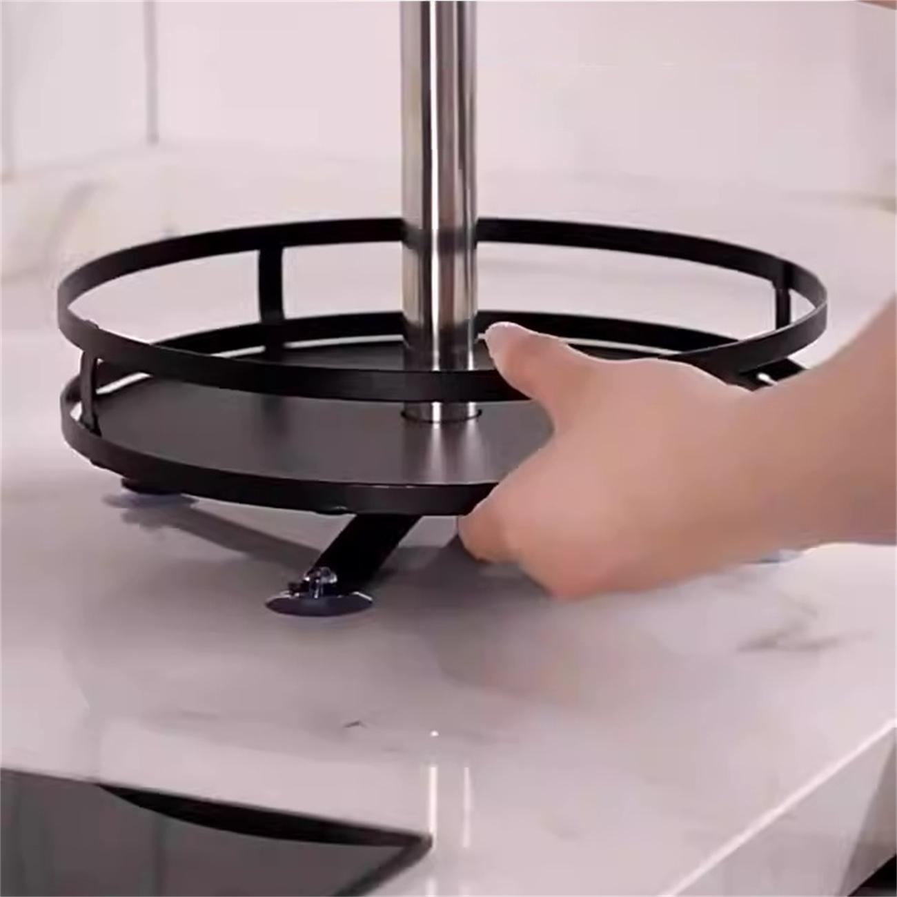 Ein schwarzes, sich drehendes Küchenregal, das von einer Hand berührt wird, auf einer weißen Marmoroberfläche.