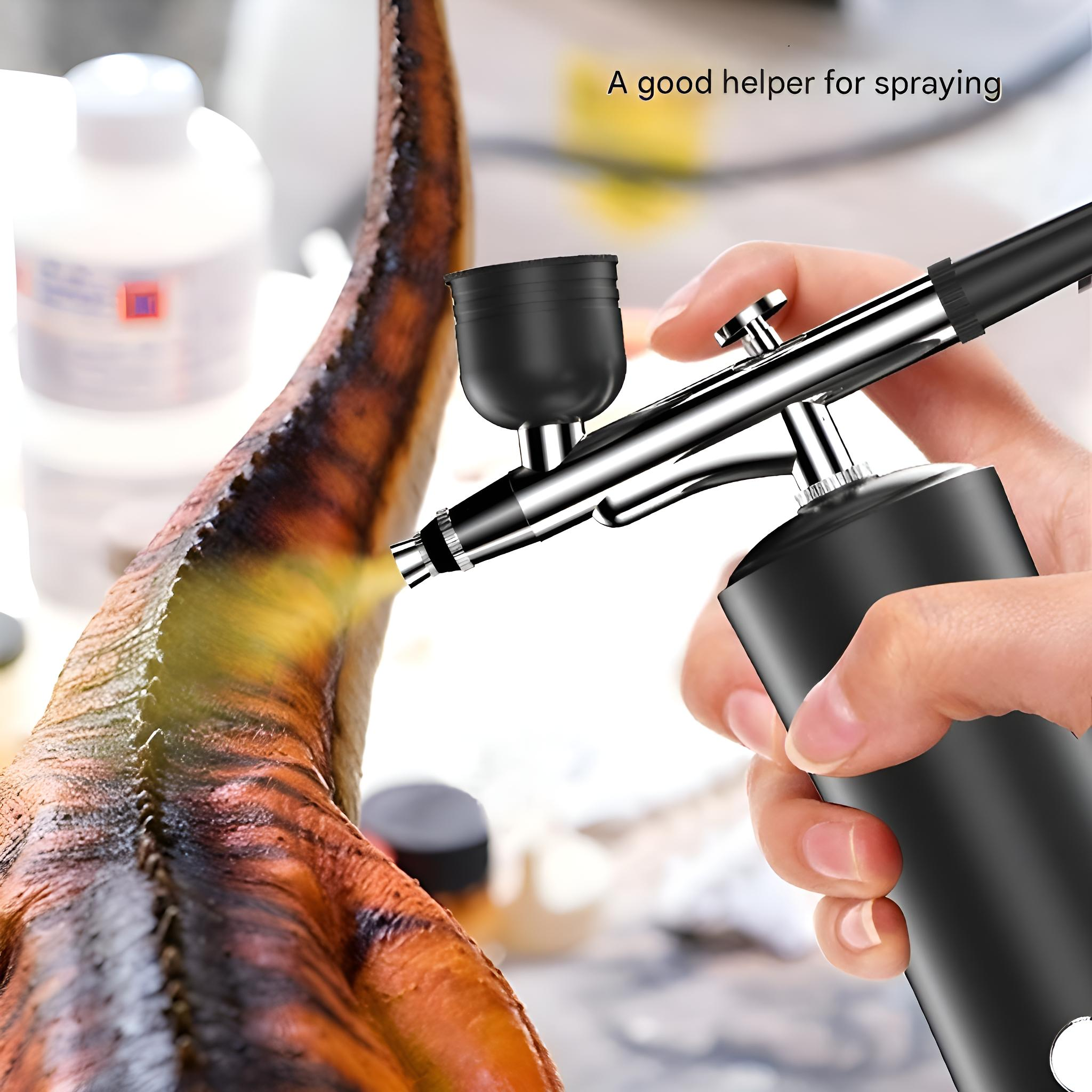 Eine Hand, die eine Airbrush hält und auf ein braunes Objekt sprüht, mit weißen Flaschen im Hintergrund.