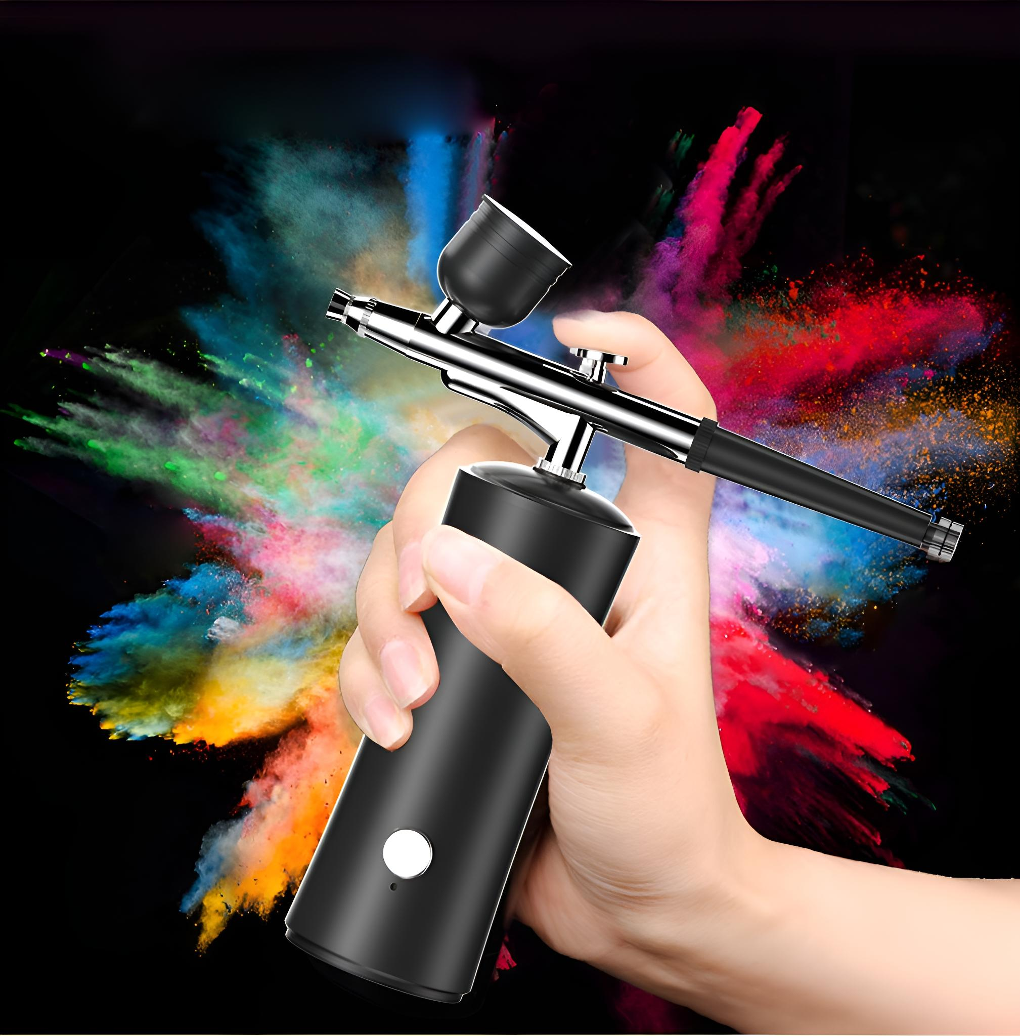 Eine Hand, die eine Airbrush hält, mit bunten Farbspritzern im Hintergrund, auf schwarzem Hintergrund.
