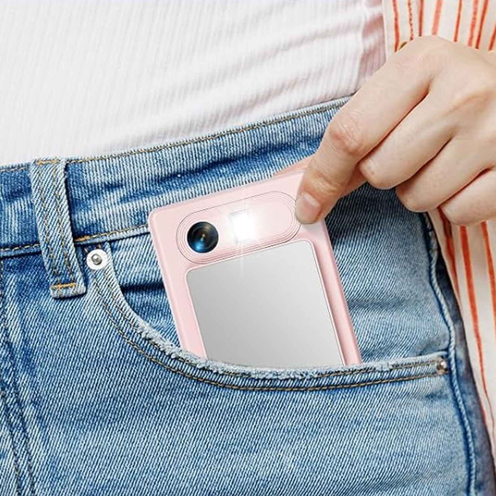Eine rosa Kamera wird aus einer Jeans-Tasche gezogen. Die Kamera ist nach außen gerichtet.