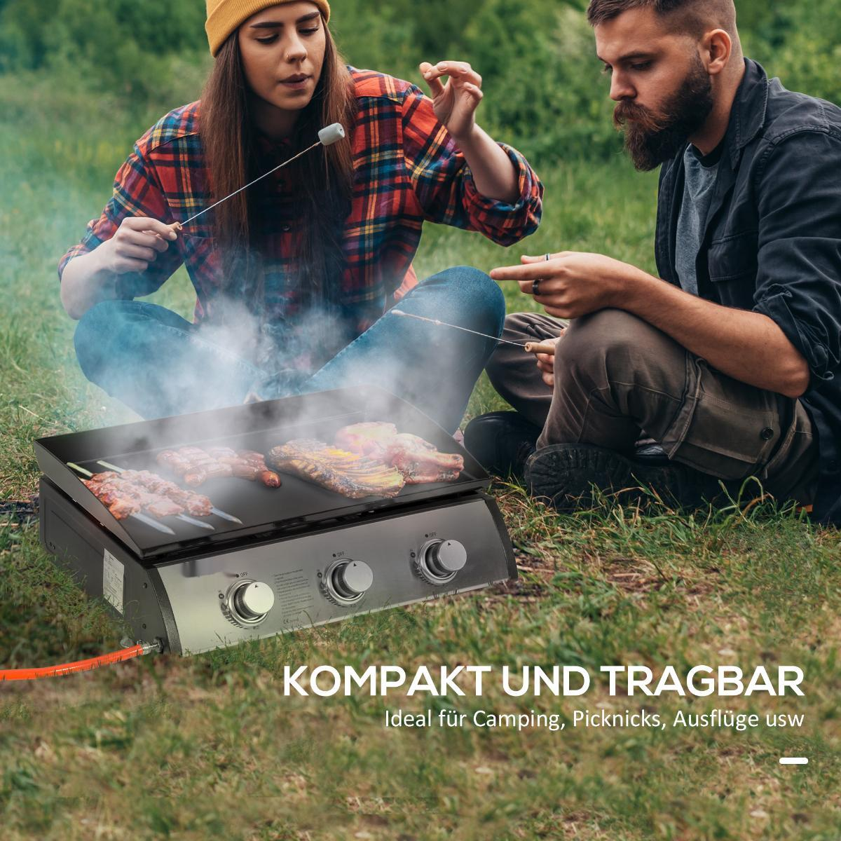 Zwei Personen grillen im Freien. Sie benutzen einen tragbaren Grill auf dem Rasen.
