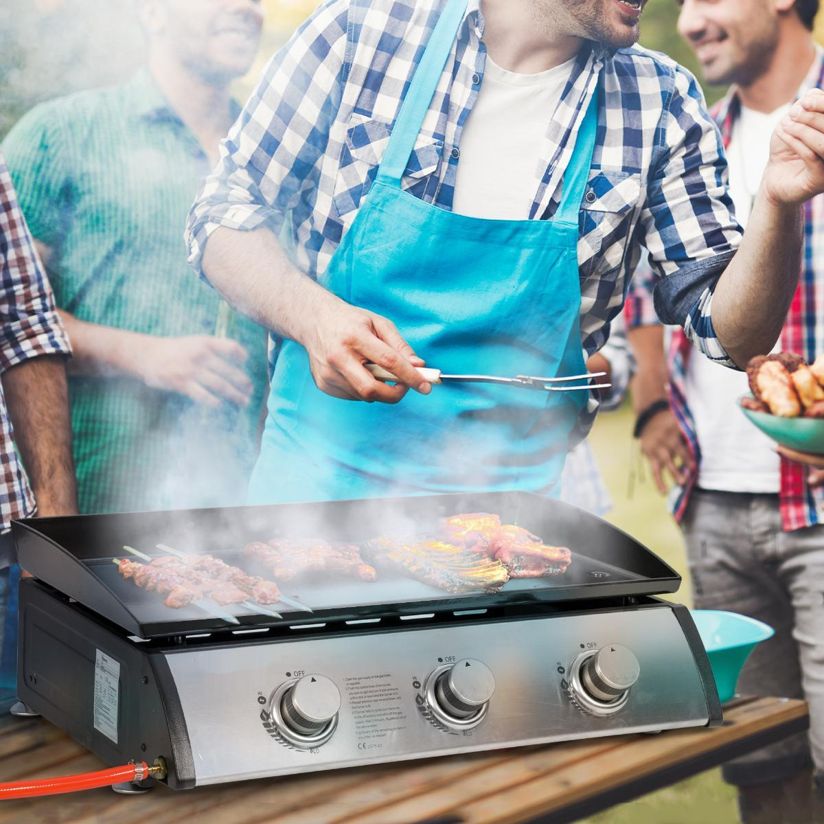 Menschen grillen im Freien. Eine Person benutzt eine Zange, um das Essen zu wenden.