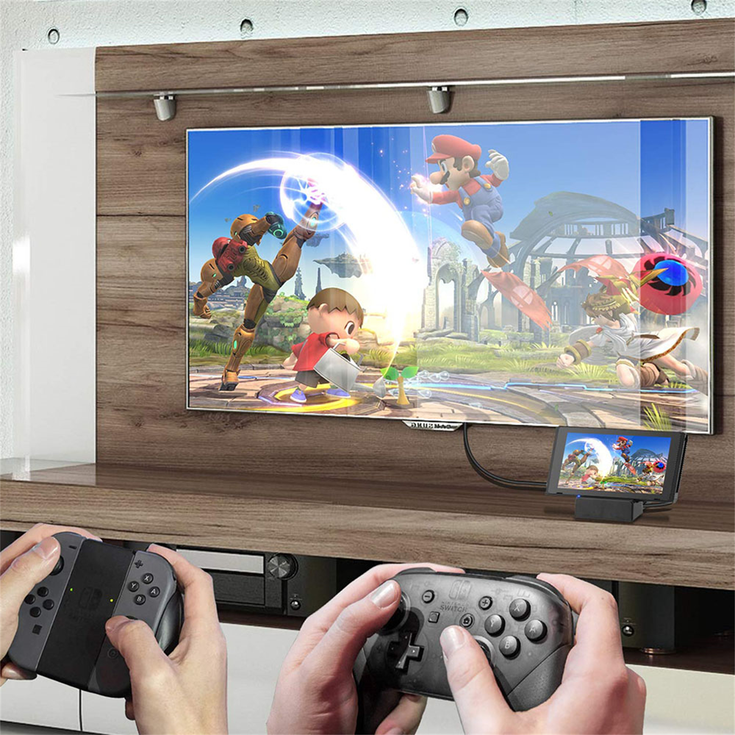 Ein Fernsehbildschirm zeigt eine Spielszene mit Charakteren. Zwei Controller und Hände sind sichtbar. Ein kleiner Bildschirm unten.
