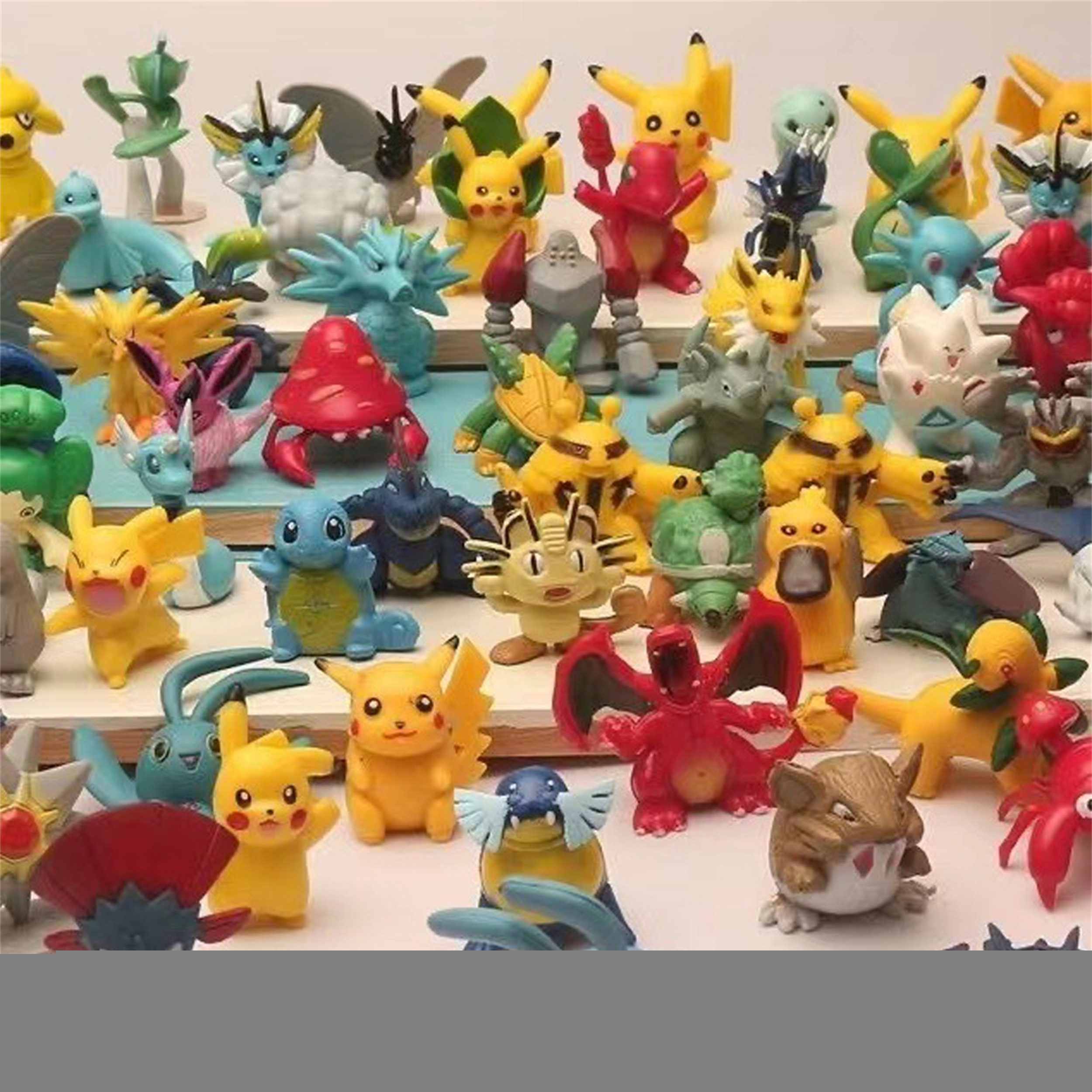 Nahaufnahme vieler kleiner Pokémon-Figuren. Verschiedene Charaktere sind auf einer Oberfläche angeordnet, farbenfroh und vielfältig.