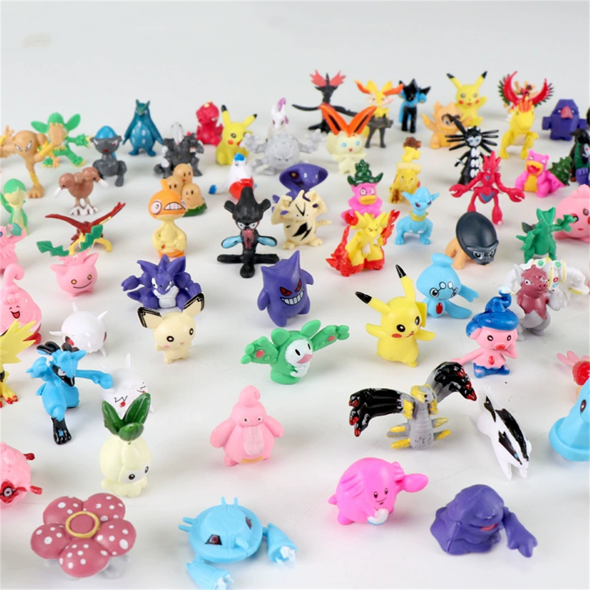 Viele kleine Pokémon-Figuren sind auf einer weißen Oberfläche angeordnet. Eine Vielzahl von Charakteren ist sichtbar.