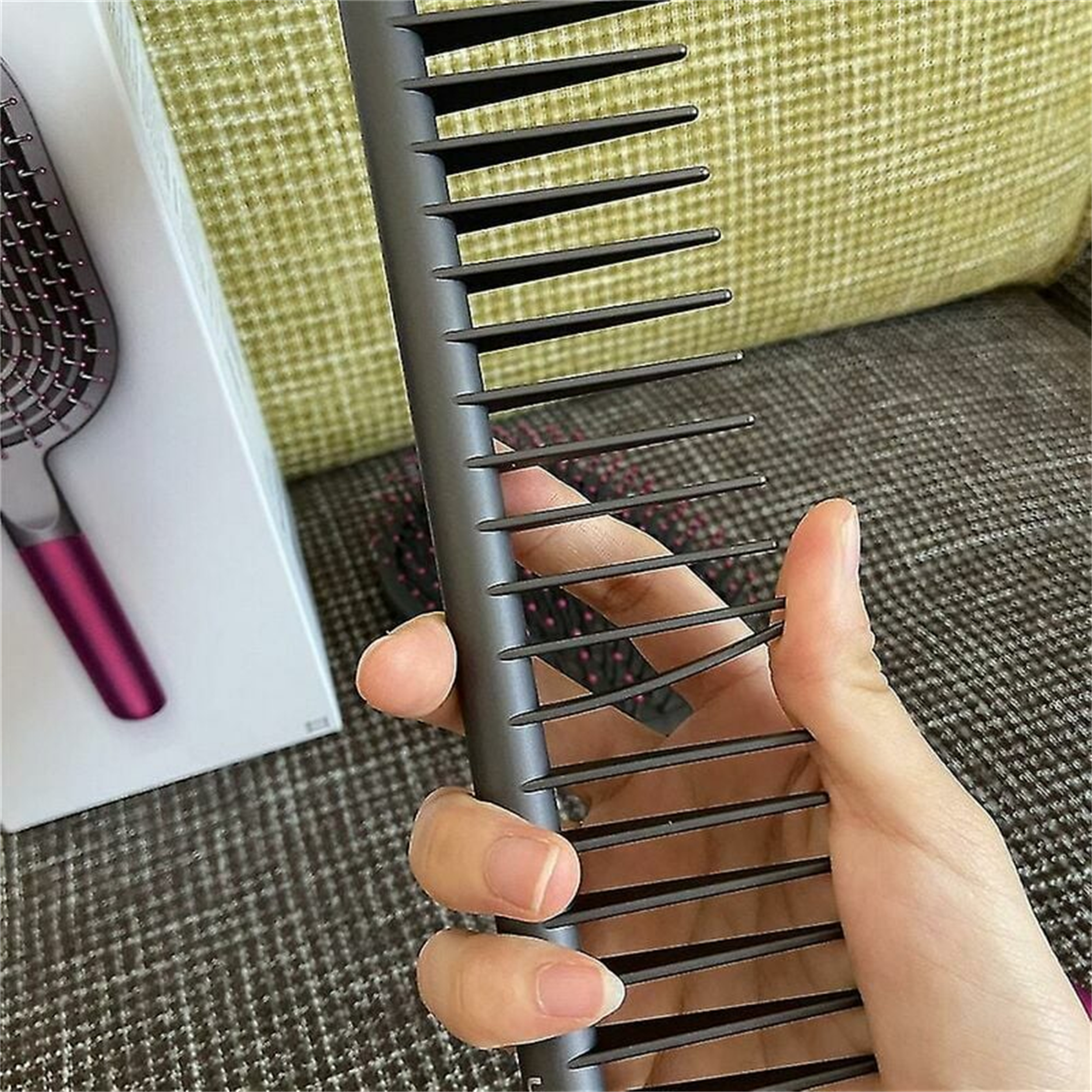 Eine Hand, die einen schwarzen Kamm aus einem Haarstyling-Set hält.
