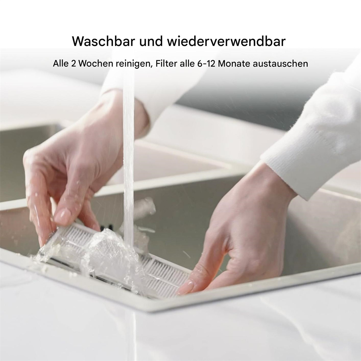 Hände waschen einen Filter in einem Waschbecken, mit Text über Reinigung und Austausch.