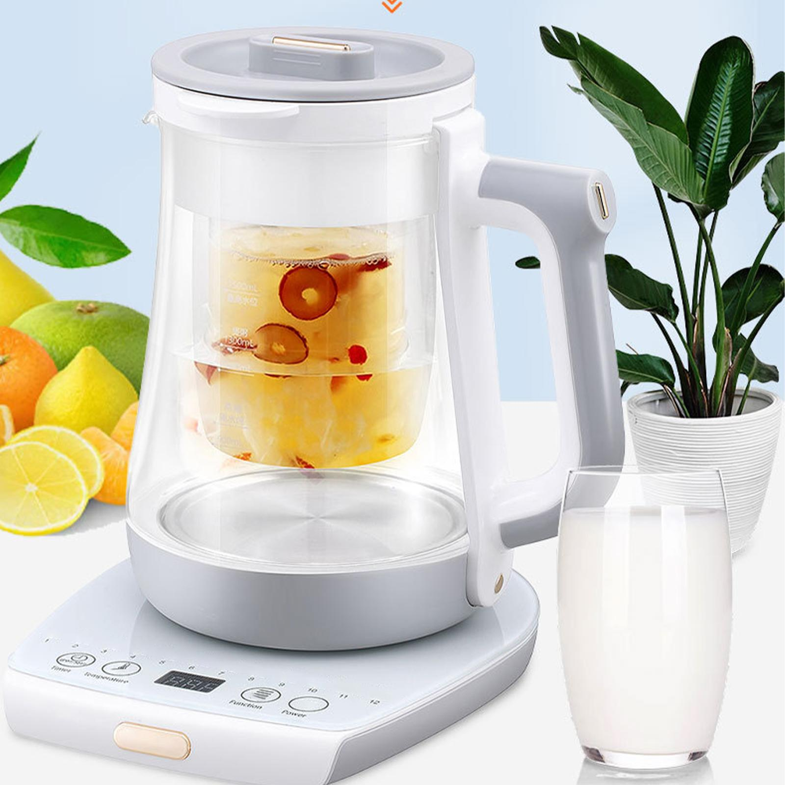 Ein Teekocher mit Tee, ein Glas Milch und eine Pflanze im Hintergrund.