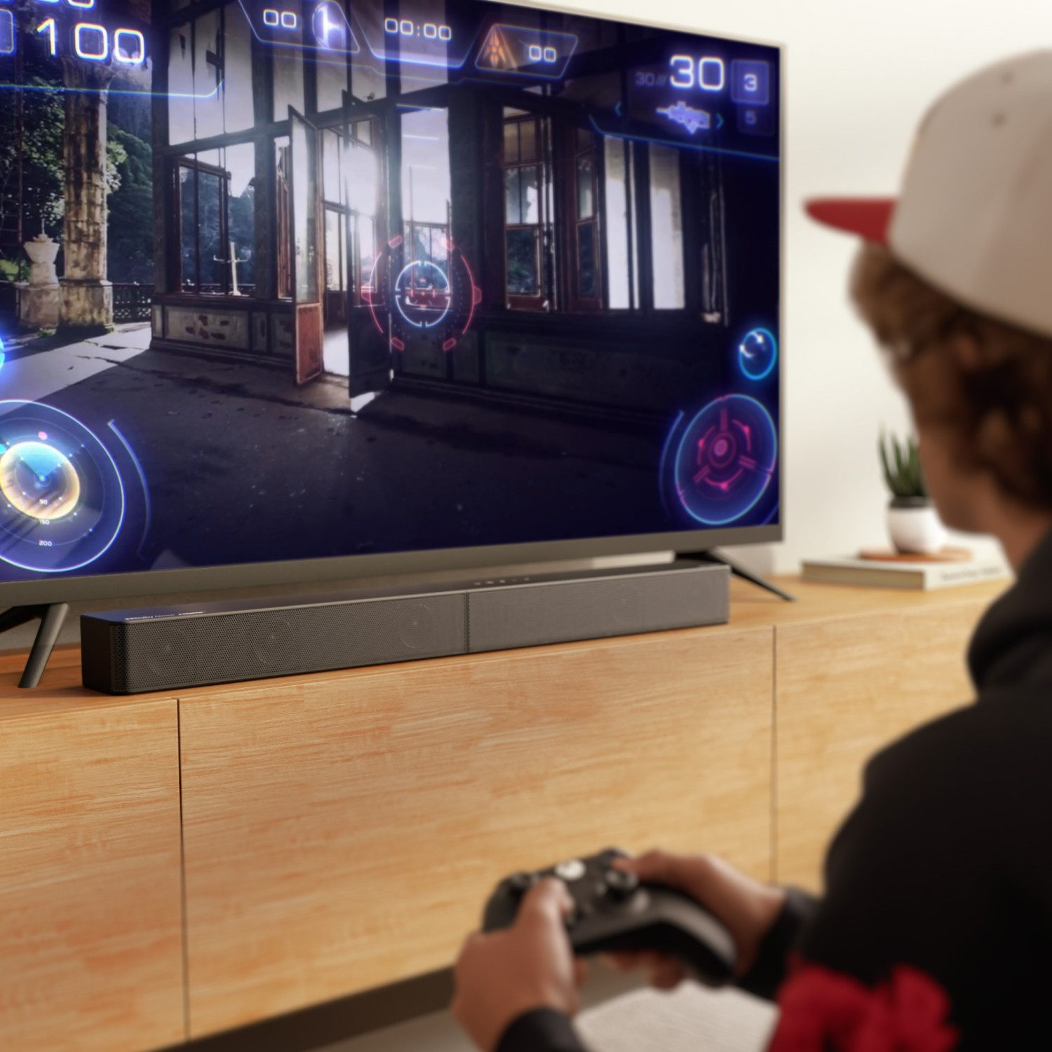 Osoba gra w grę na telewizorze. Soundbar jest na szafce pod telewizorem.