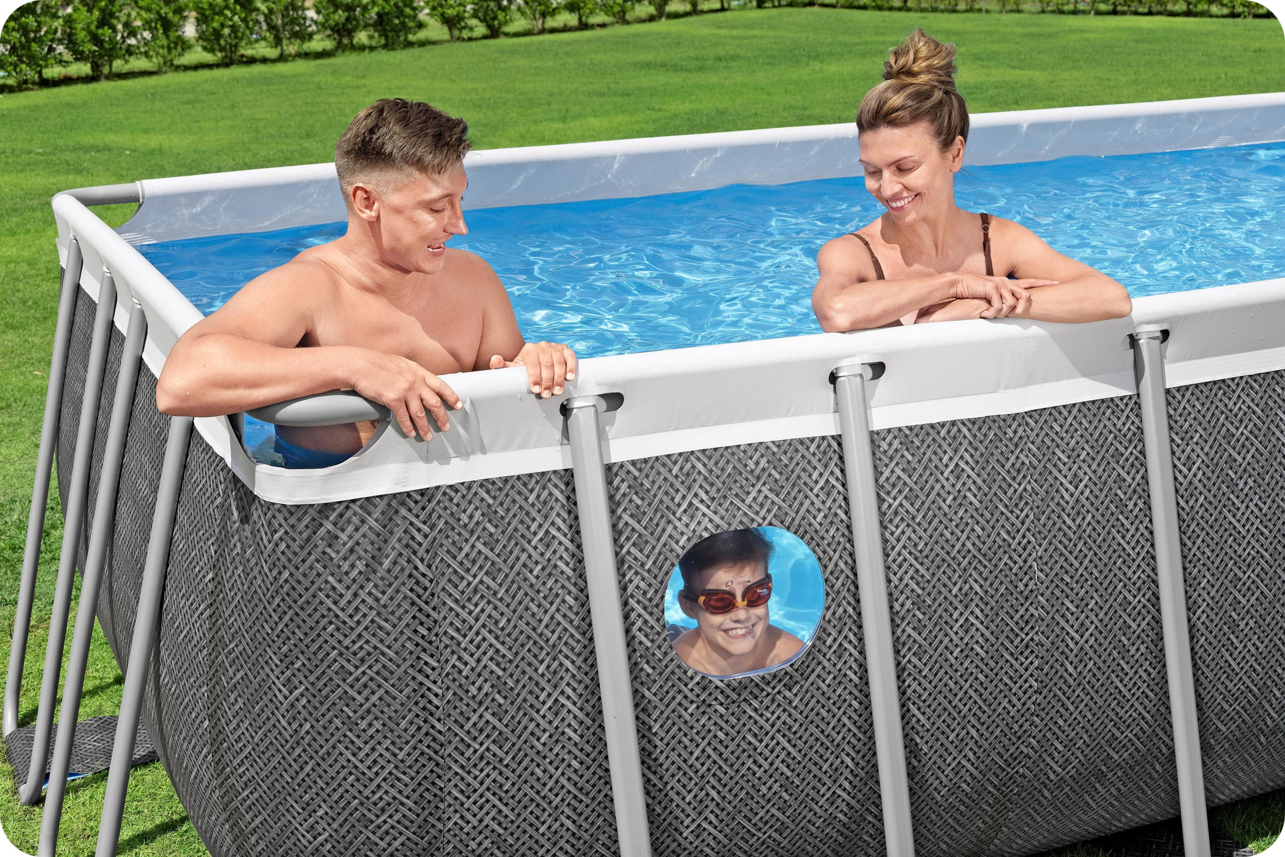 Rodzina jest w basenie. Dziecko patrzy przez otwór w ścianie basenu.