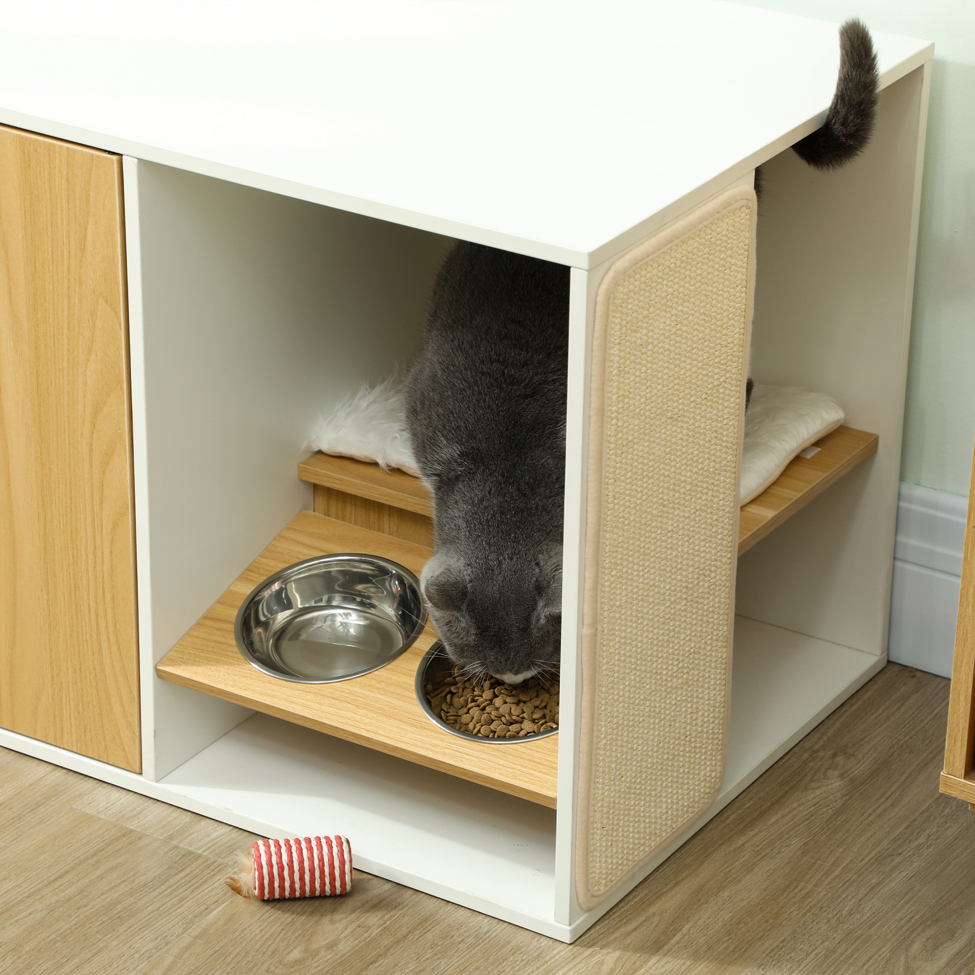 Muebles para gatos con un gato comiendo de un cuenco. Hay un rascador.