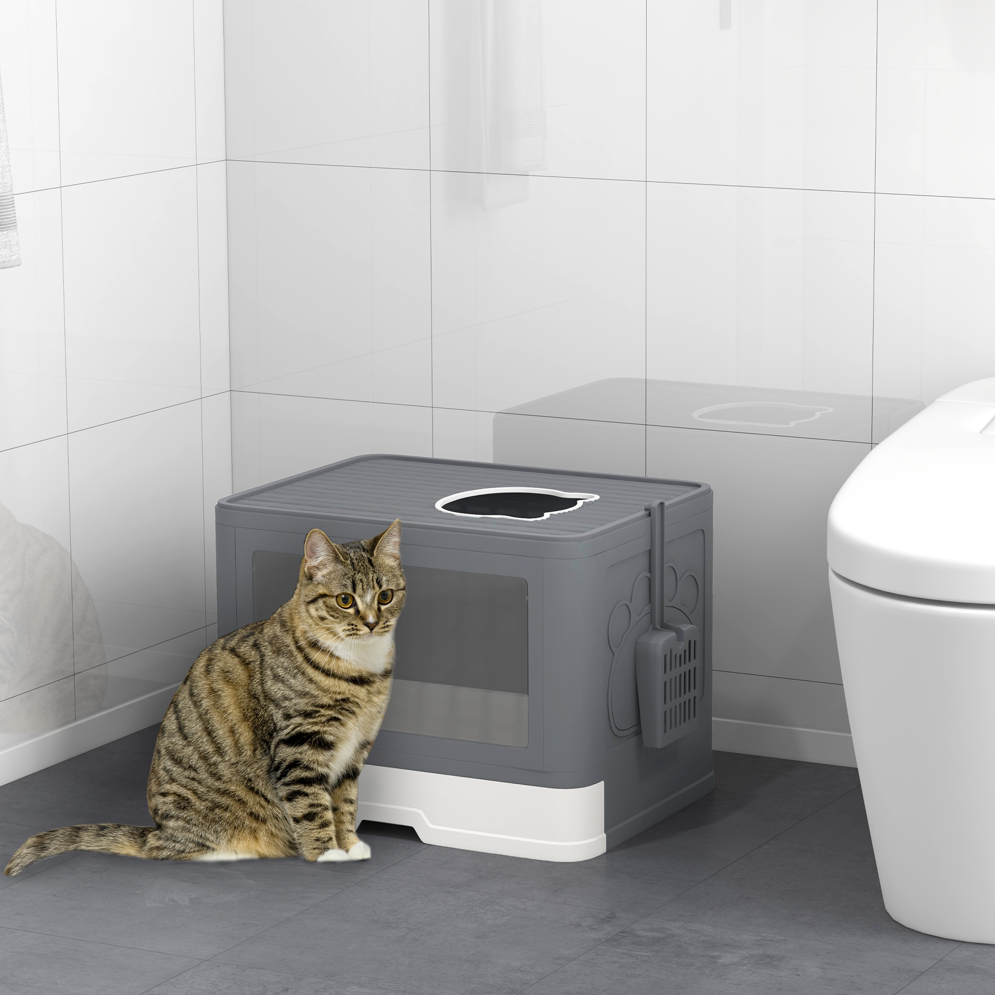 Un gato atigrado sentado junto a un arenero gris.