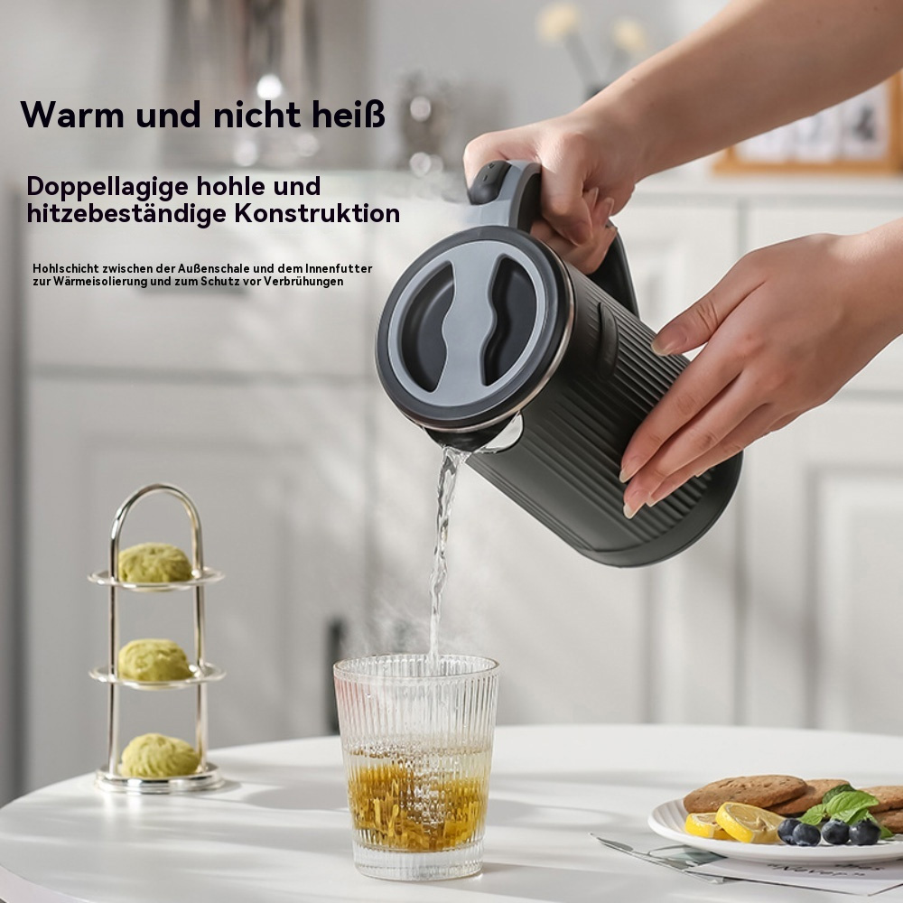 Eine Person gießt Wasser aus einem schwarzen Wasserkocher in ein Glas. Andere Gegenstände wie ein Dessertständer, Zitronen und ein Teller sind sichtbar.