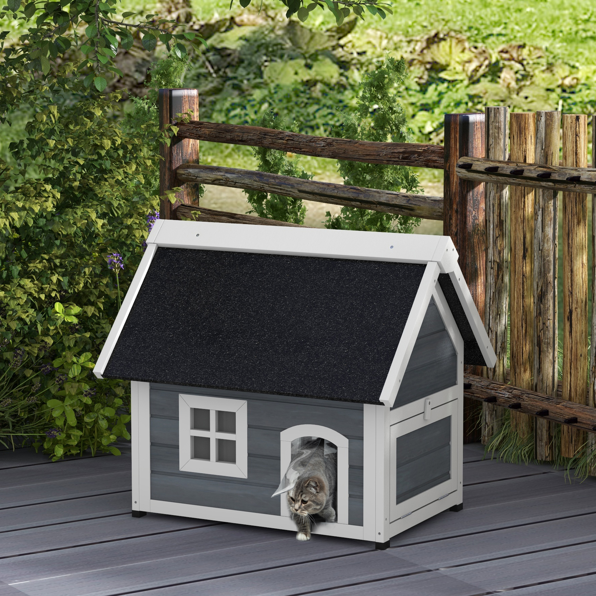 Una casa para gatos con un gato en la puerta. La casa es gris y blanca con un techo negro.