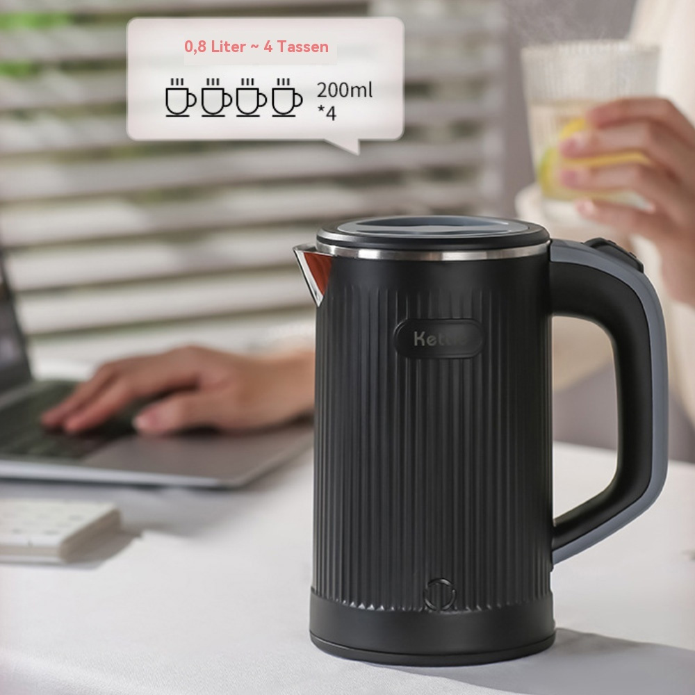 Ein schwarzer Wasserkocher steht auf einem weißen Tisch mit einem Laptop und einer Person, die im Hintergrund ein Glas Wasser hält.