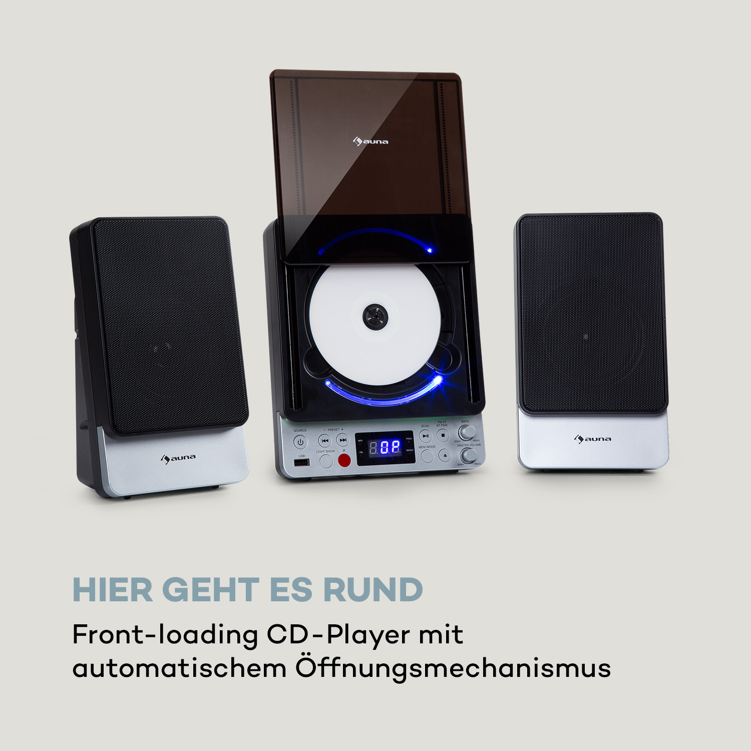 Drei Lautsprecher mit silbernen Sockeln. Der mittlere Lautsprecher hat eine geöffnete CD und ein beleuchtetes Display.