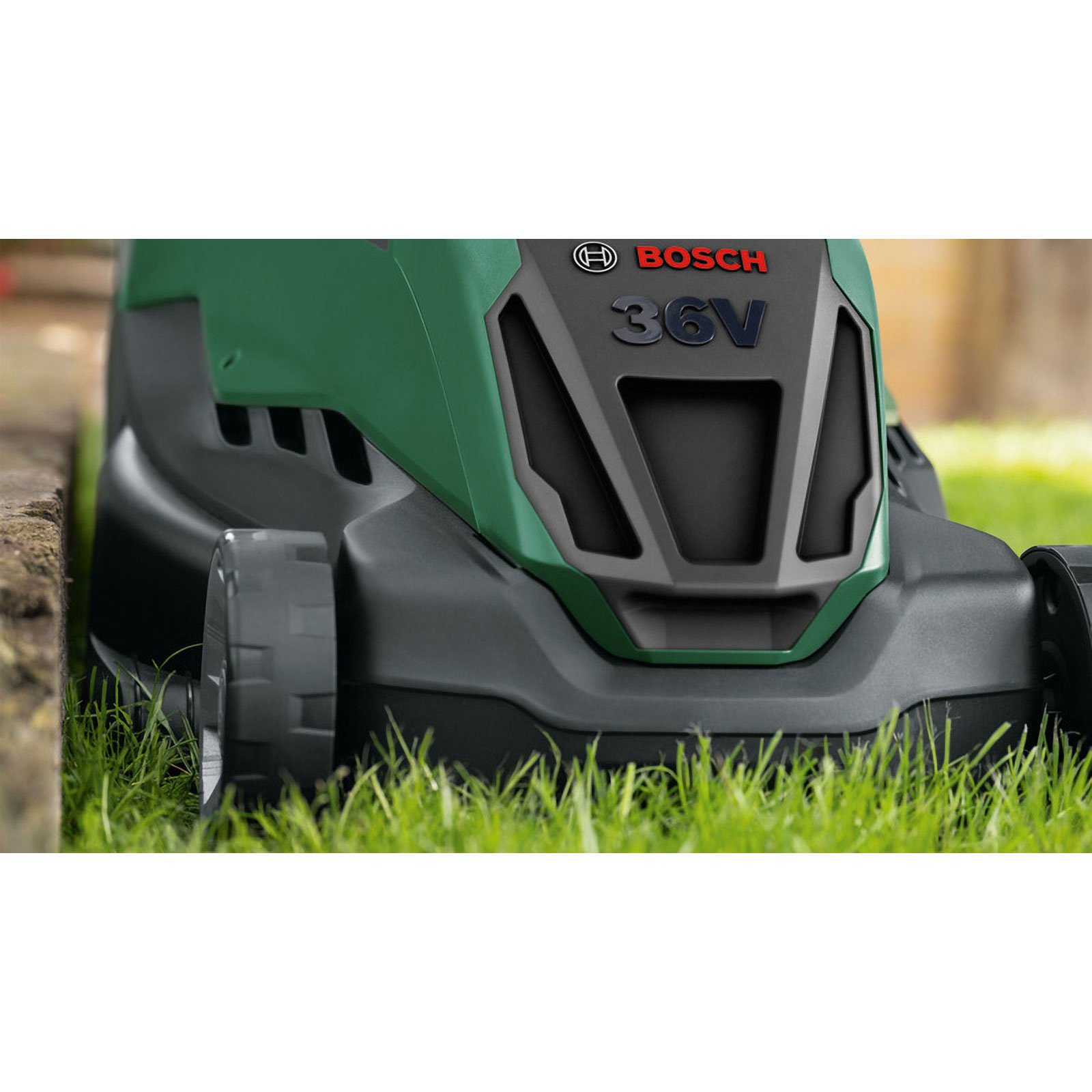 Nahaufnahme eines grün-schwarzen Rasenmähers. Die Marke Bosch ist sichtbar. Der Mäher steht auf Gras. 36V ist darauf geschrieben.