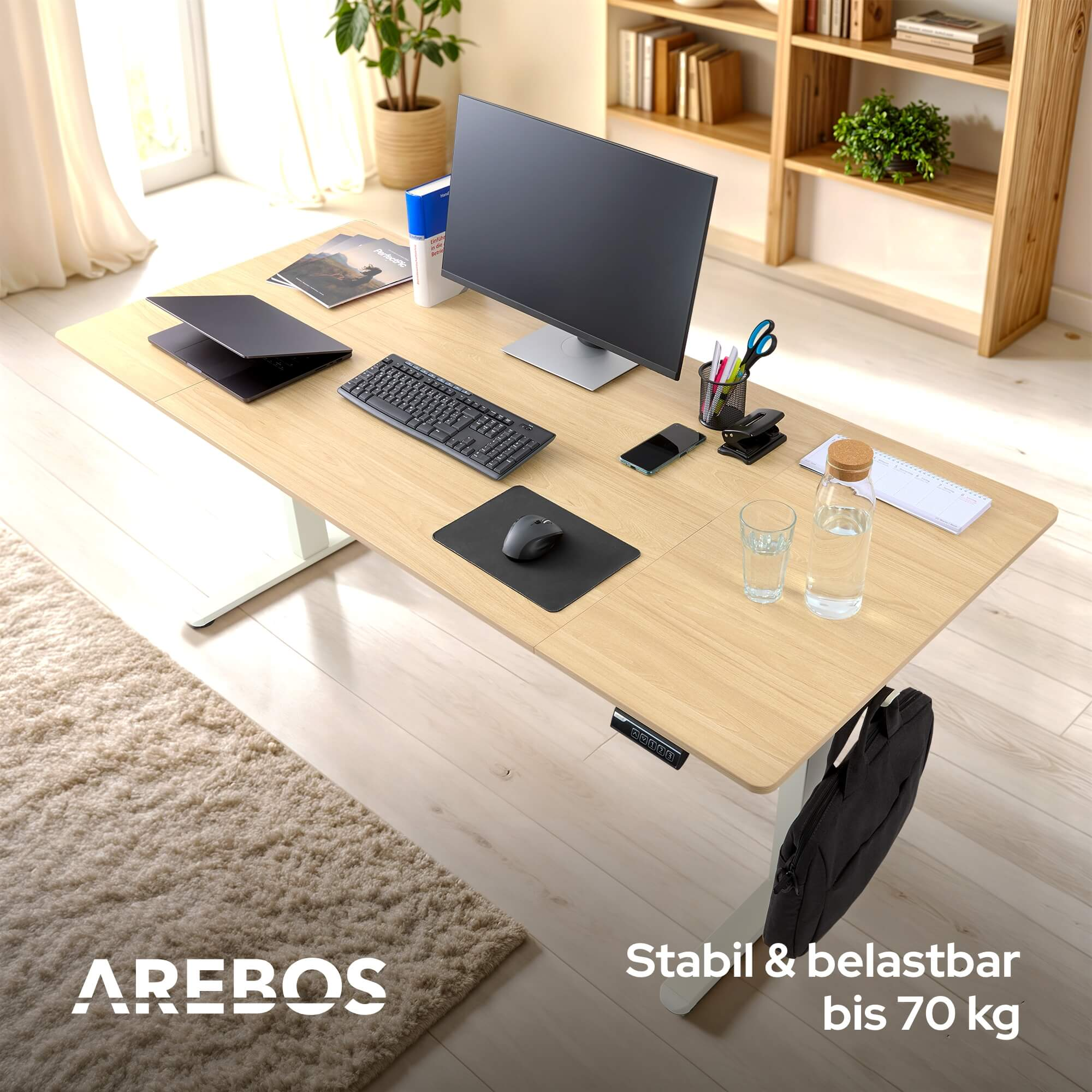 Bürotisch mit Computer, Tastatur und Zubehör. Eine Wasserflasche und ein Glas stehen auf dem Schreibtisch.