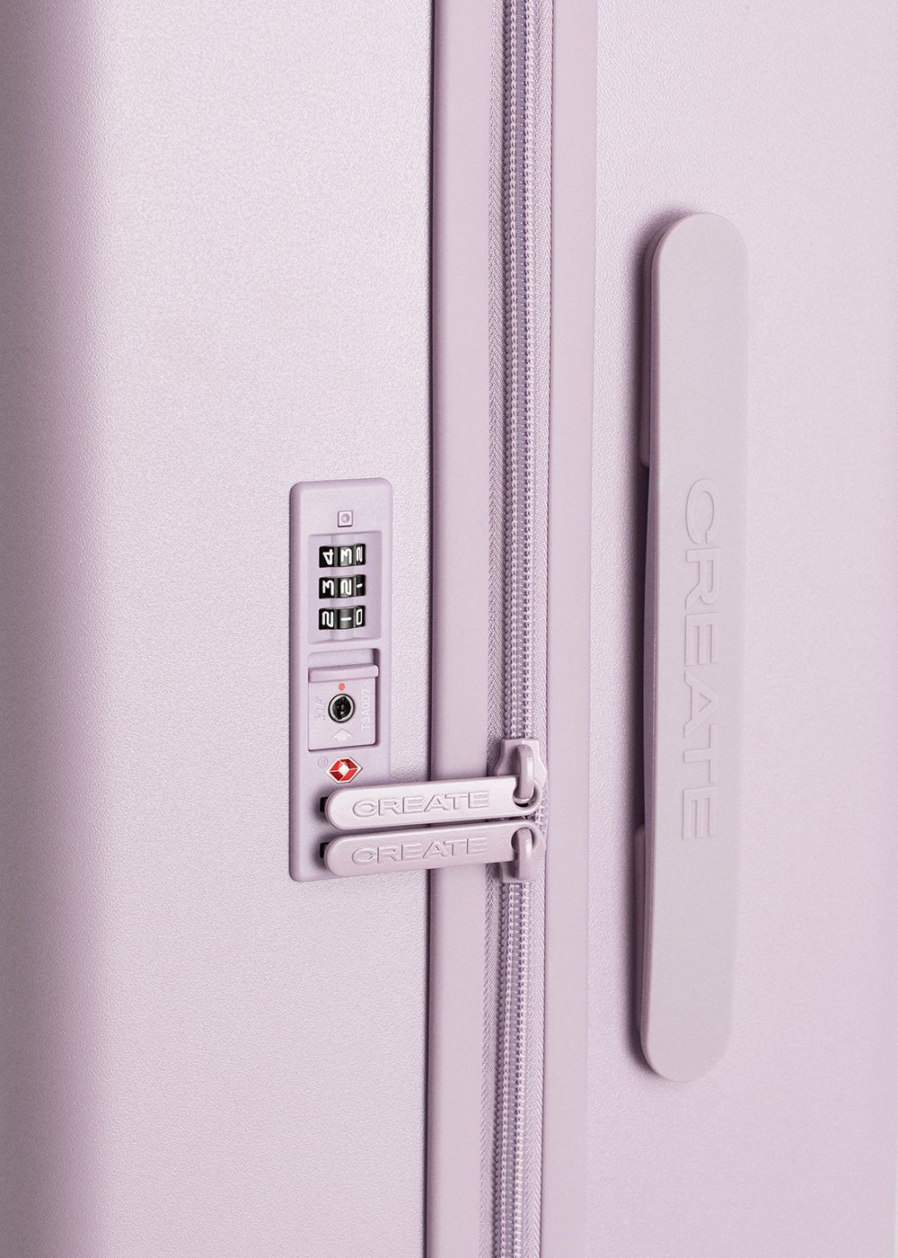 Primer plano de la cerradura de una maleta color lavanda, que muestra el dial de combinación y la marca 'CREATE', enfatizando la seguridad y los detalles de diseño.
