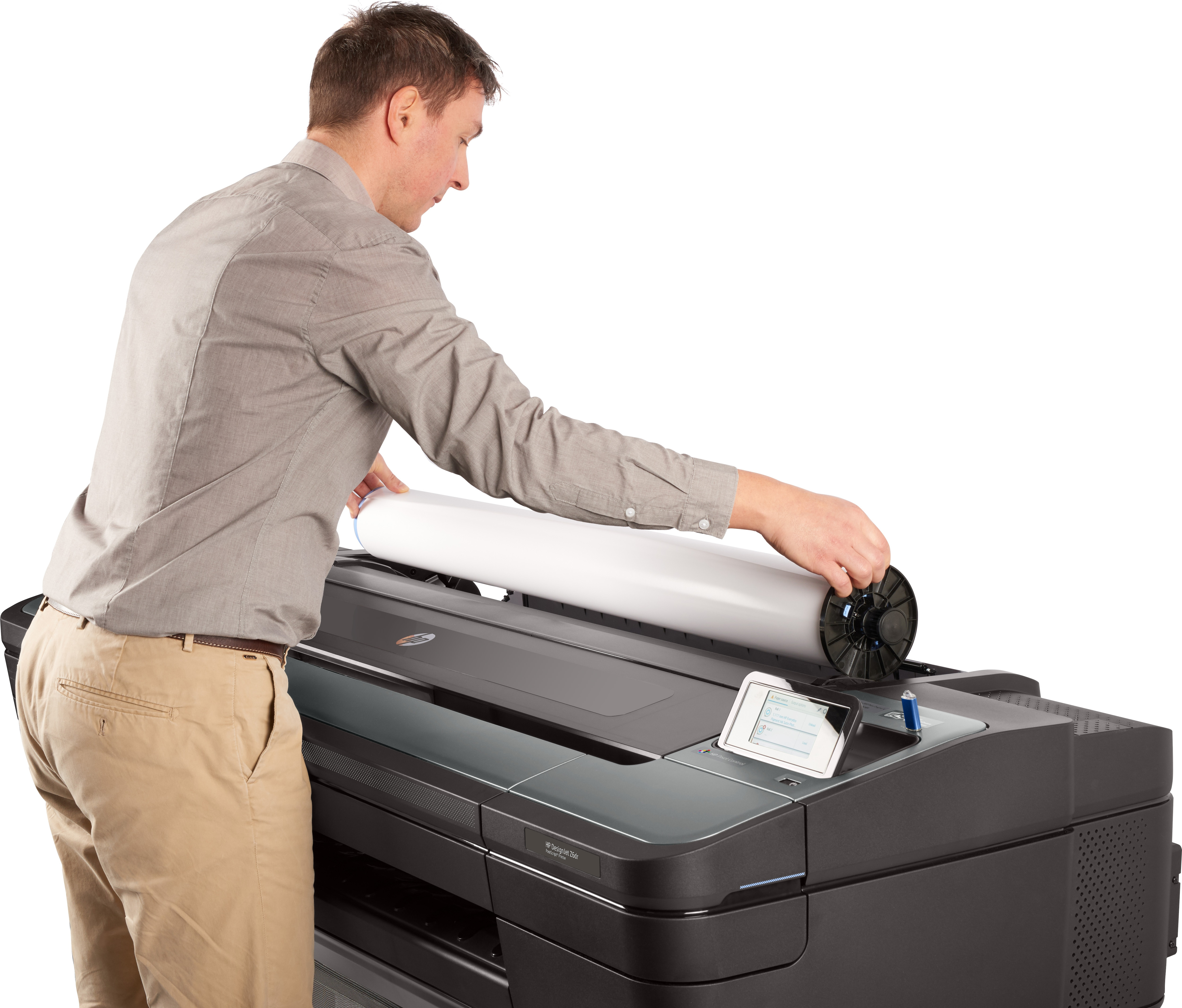 Een man laadt een grote rol papier in een grootformaatprinter.
