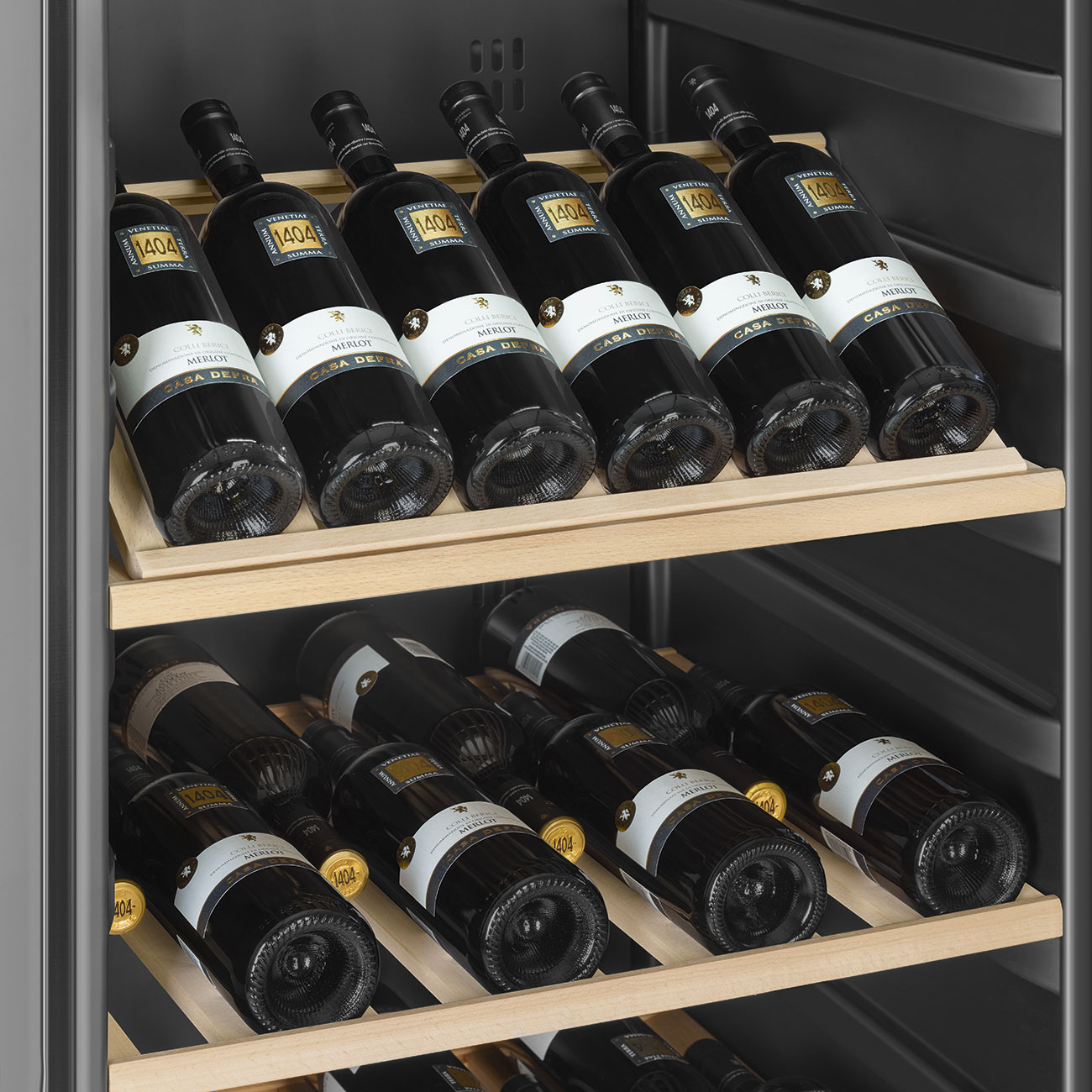 Primer plano de botellas de vino en estantes de madera dentro de una vinoteca. Botellas oscuras con etiquetas blancas.